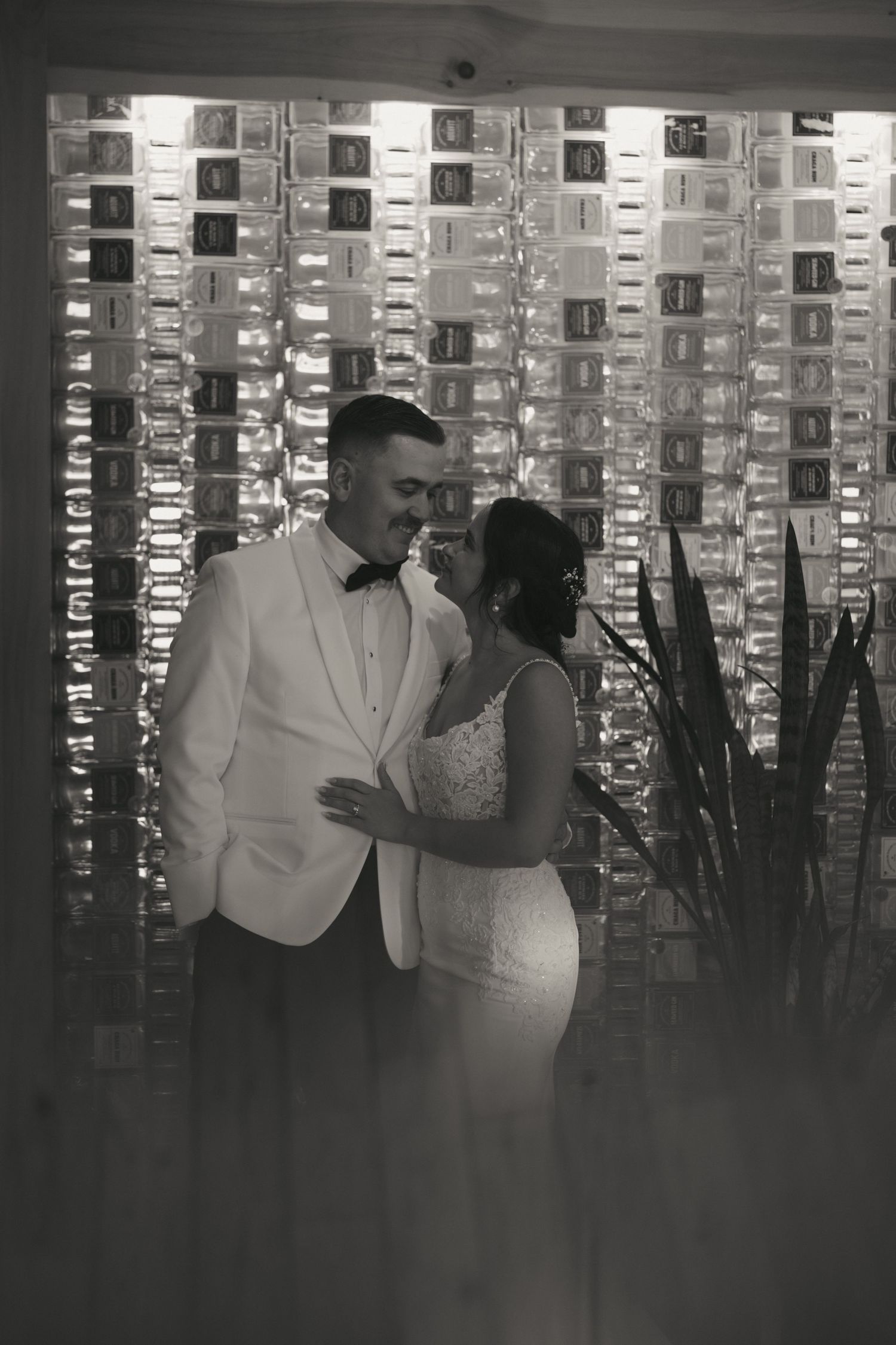 Black and white photo series showing a couple dancing in formal attire in front of an illuminated wall display.