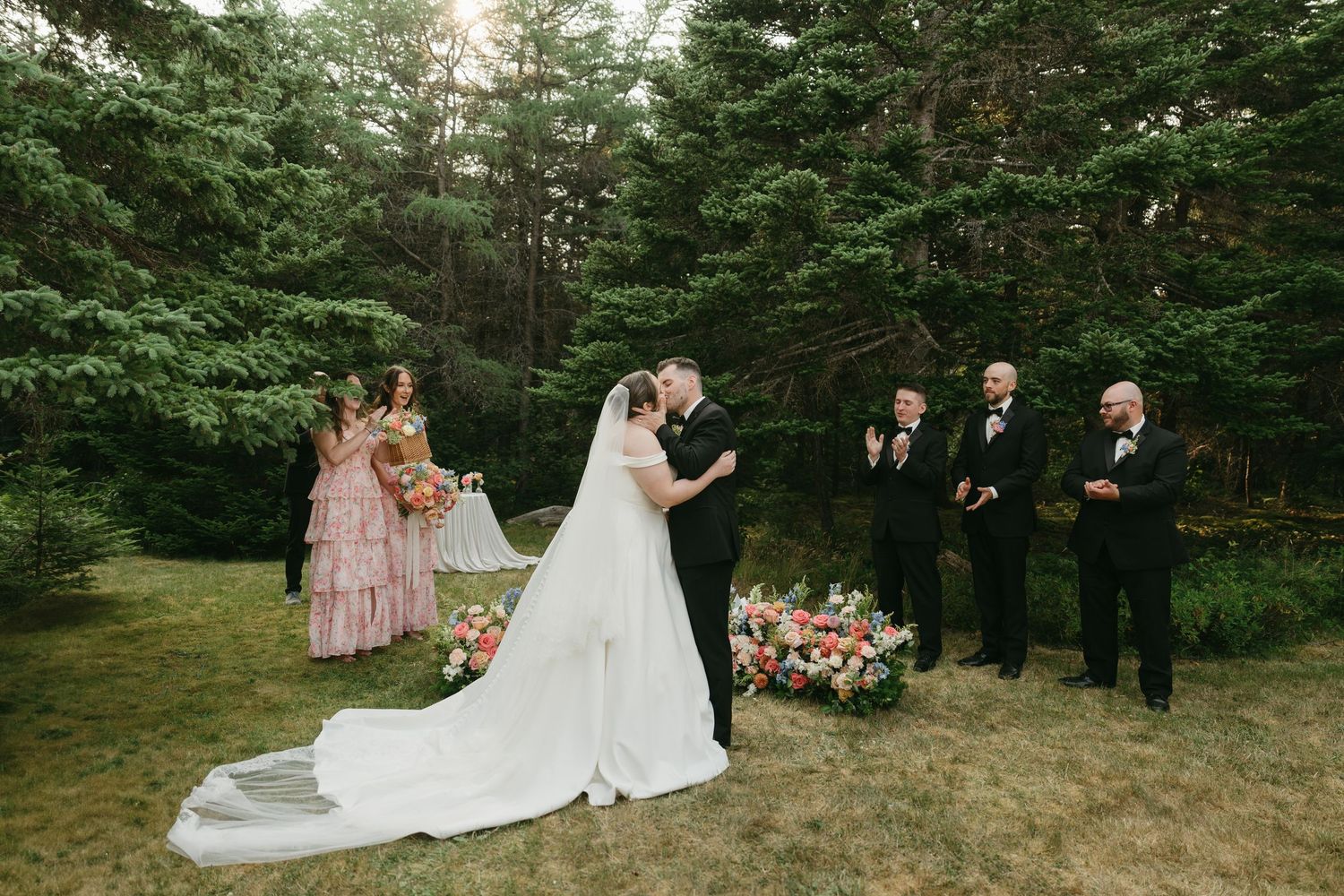 Wedding ceremony setup in a beautiful outdoor forest setting with white chairs and floral arrangements.