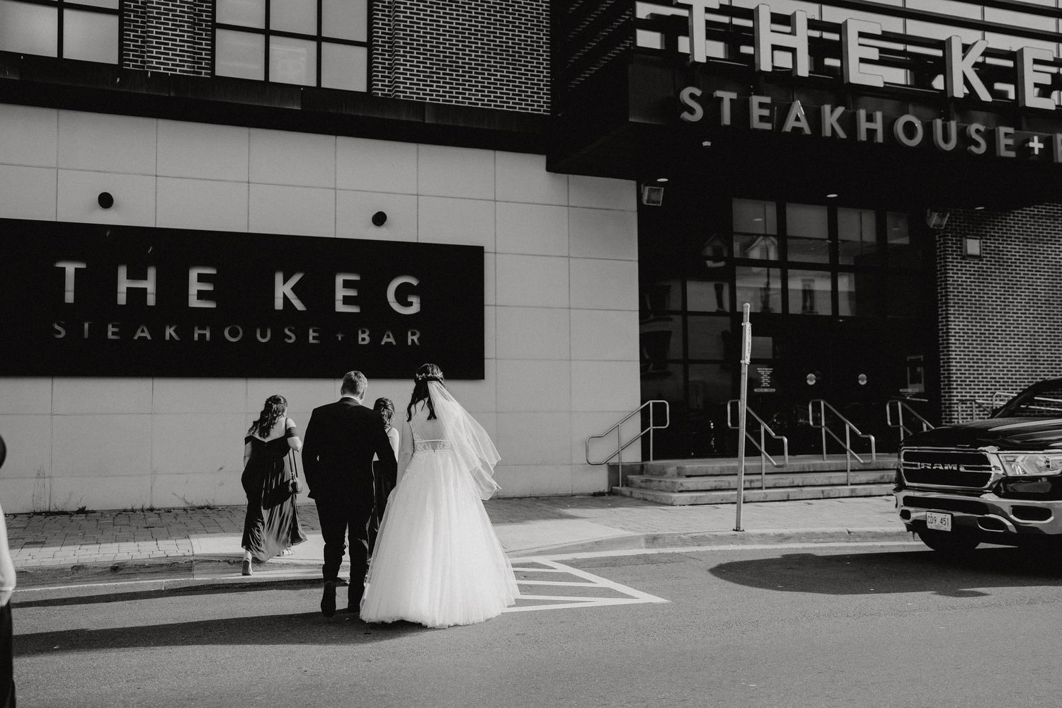 A wedding party entering The Keg steakhouse restaurant on a city street.
