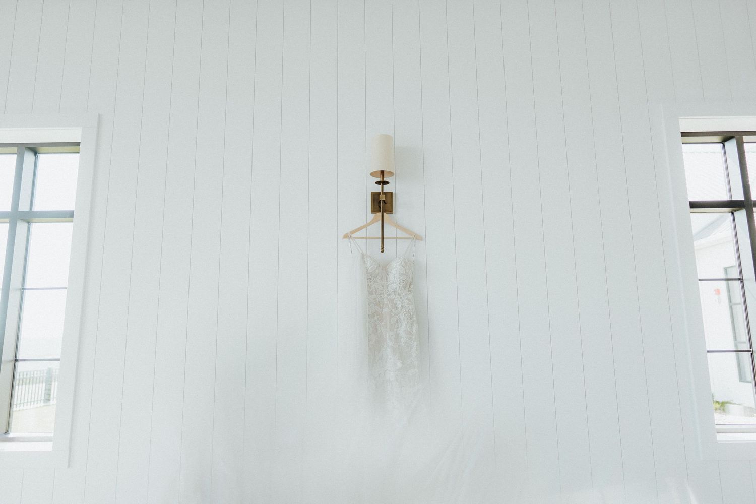 Minimalist white room interior with windows and hanging dress.