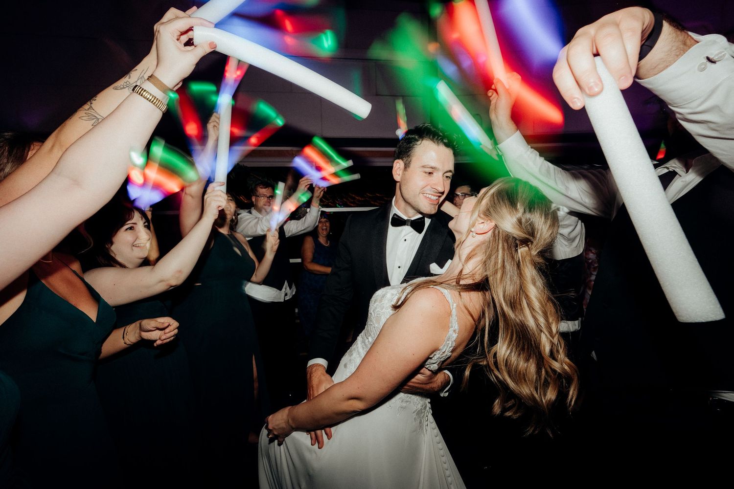 Colorful party scene with glow sticks and dancing at a wedding reception.