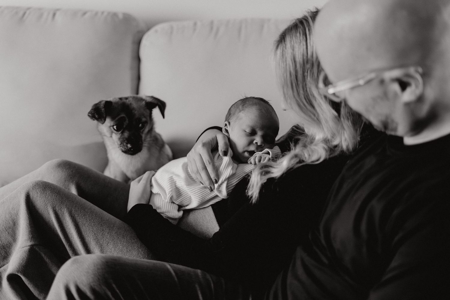 Monochrome photograph showing quiet family interactions on a sofa.