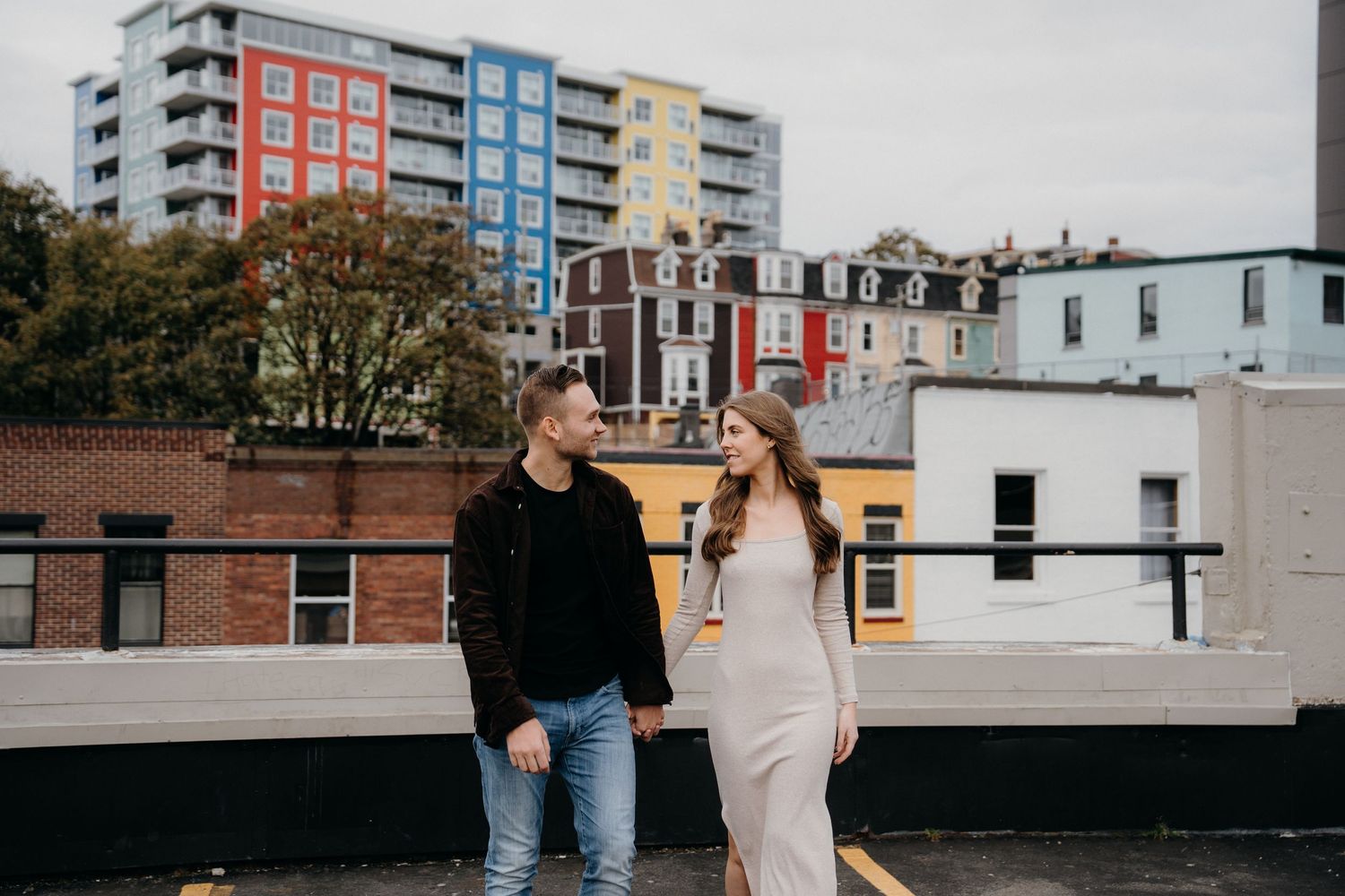Romantic rooftop photoshoot with city apartment buildings creating colorful backdrop.