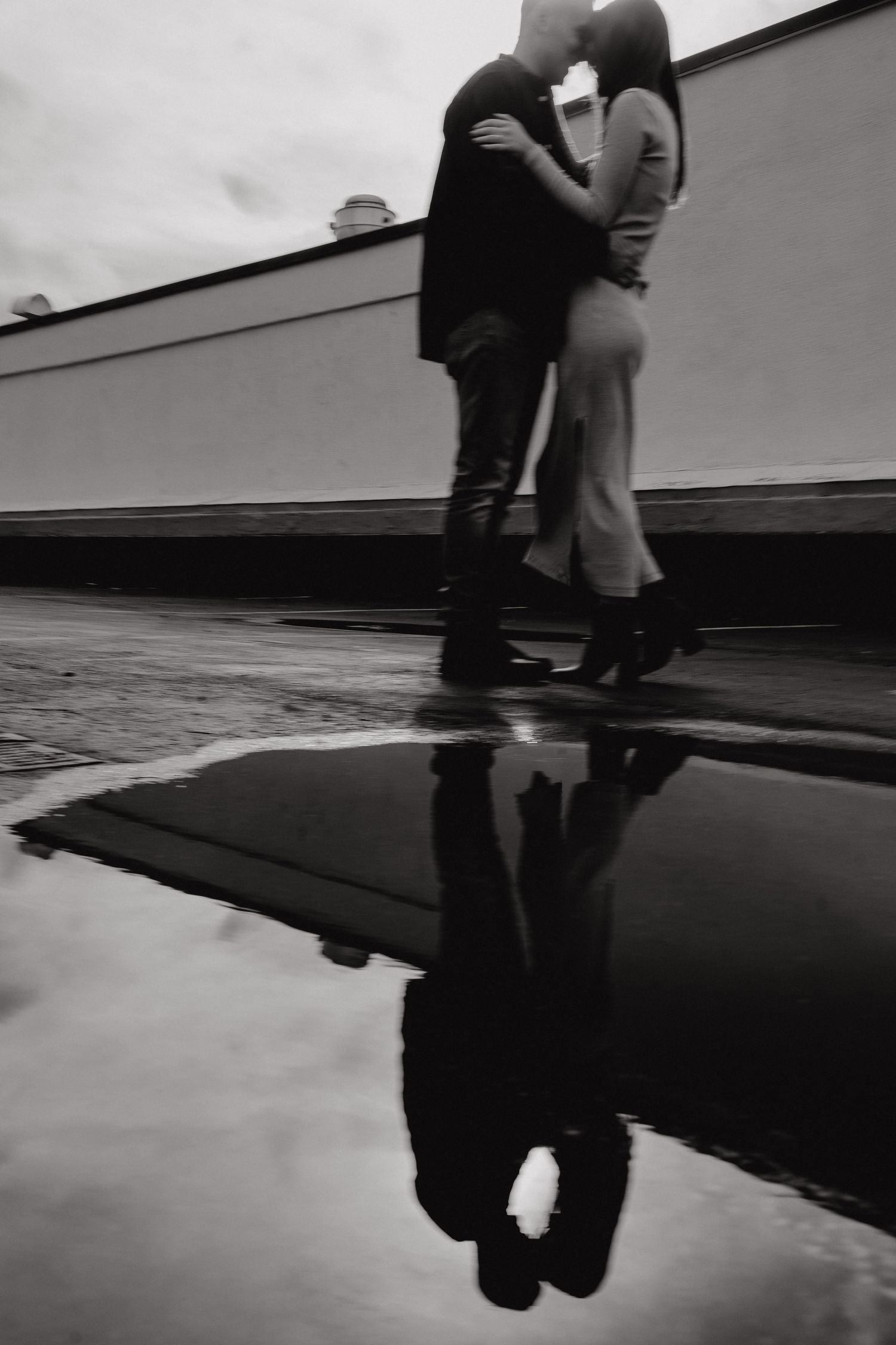 Dramatic black and white photo capturing a couple's silhouette and reflection in urban setting.