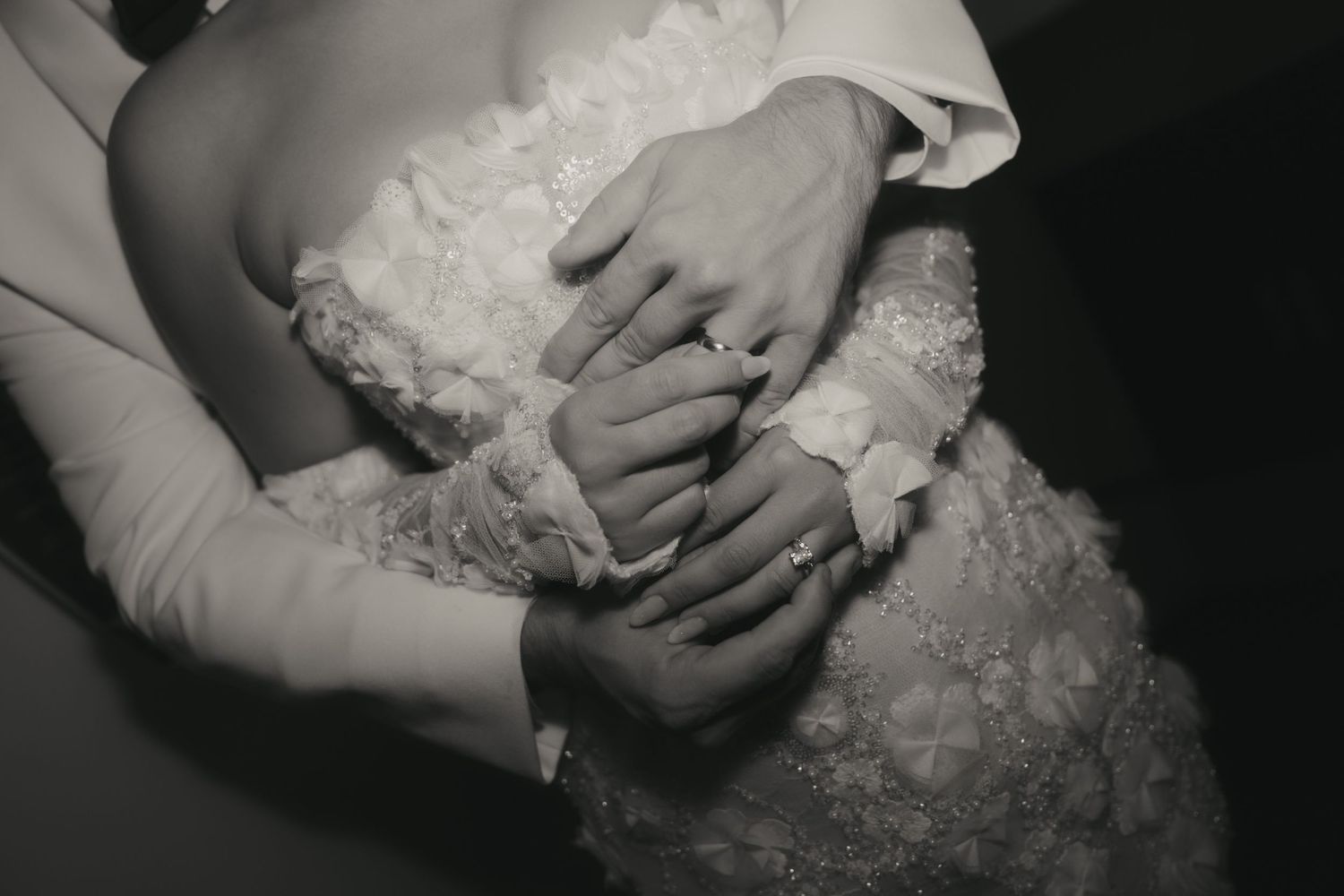 Close-up detail shots of hands holding delicate white lace fabric from a wedding dress.