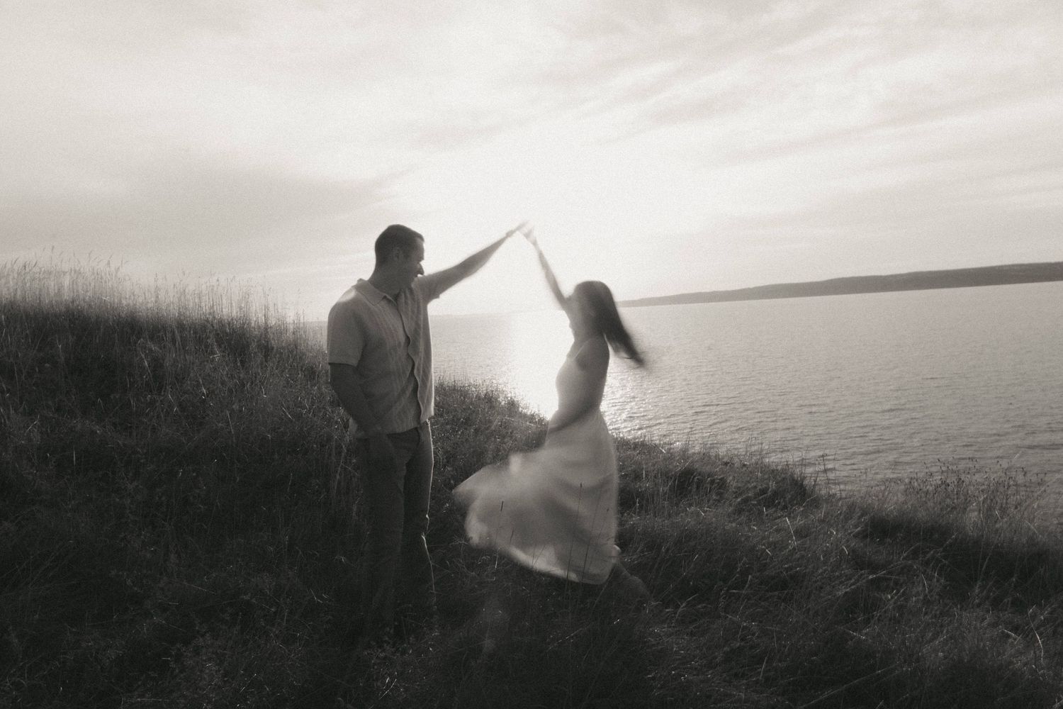 A series of silhouetted figures stand along a misty coastal cliff edge at sunset creating a dreamy atmosphere.