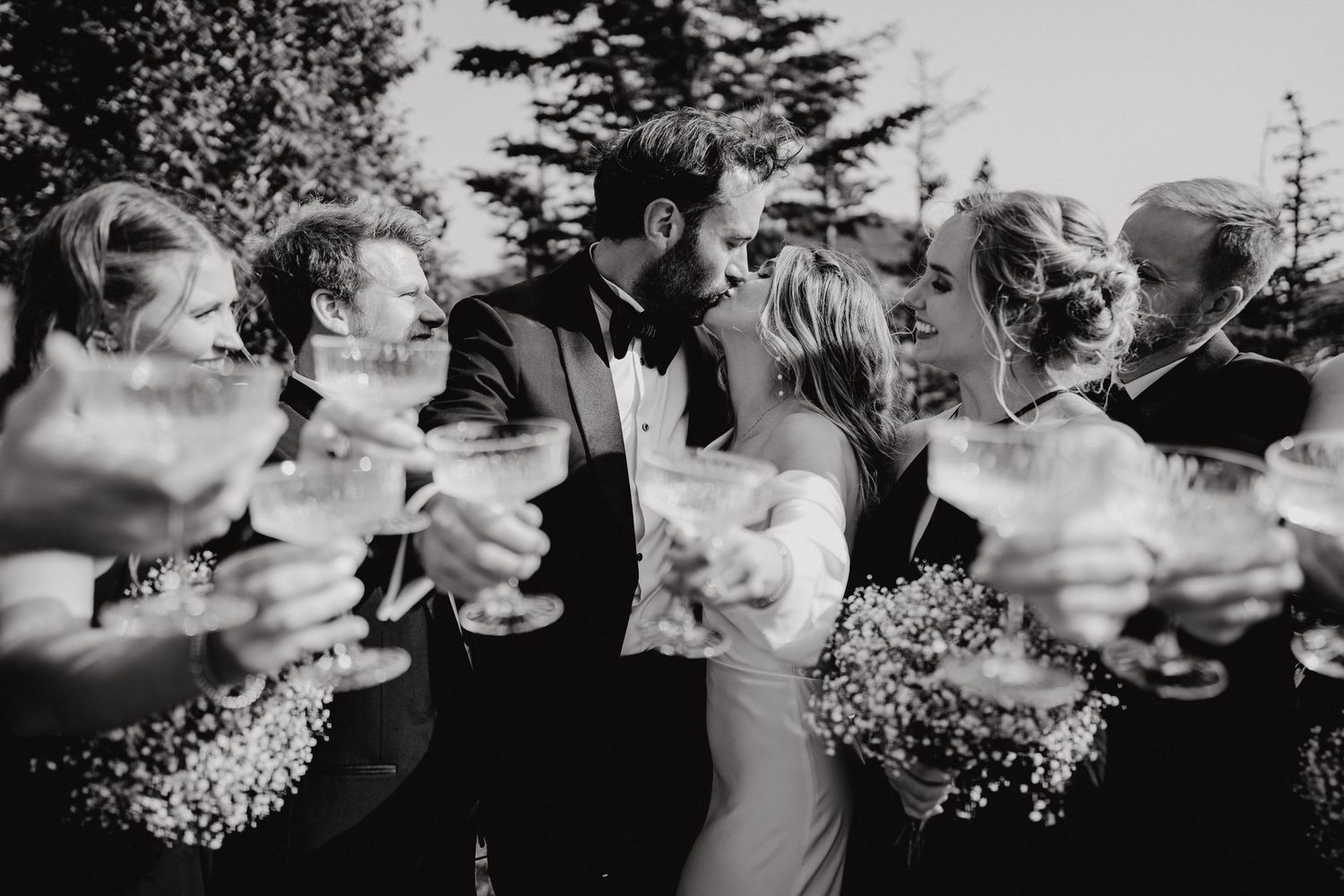 Wedding party toasts with champagne glasses in black and white photography.