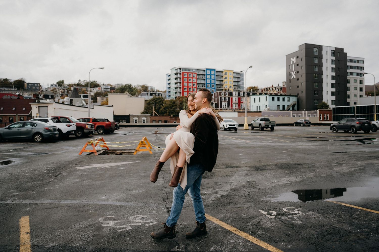 Two people share an intimate dance moment on an urban rooftop with cityscape views.