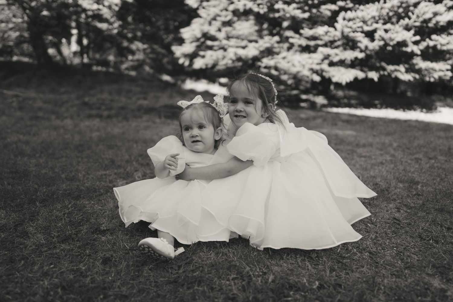 A series of vintage black and white photographs showing a baby in white clothing playing on grass outdoors.