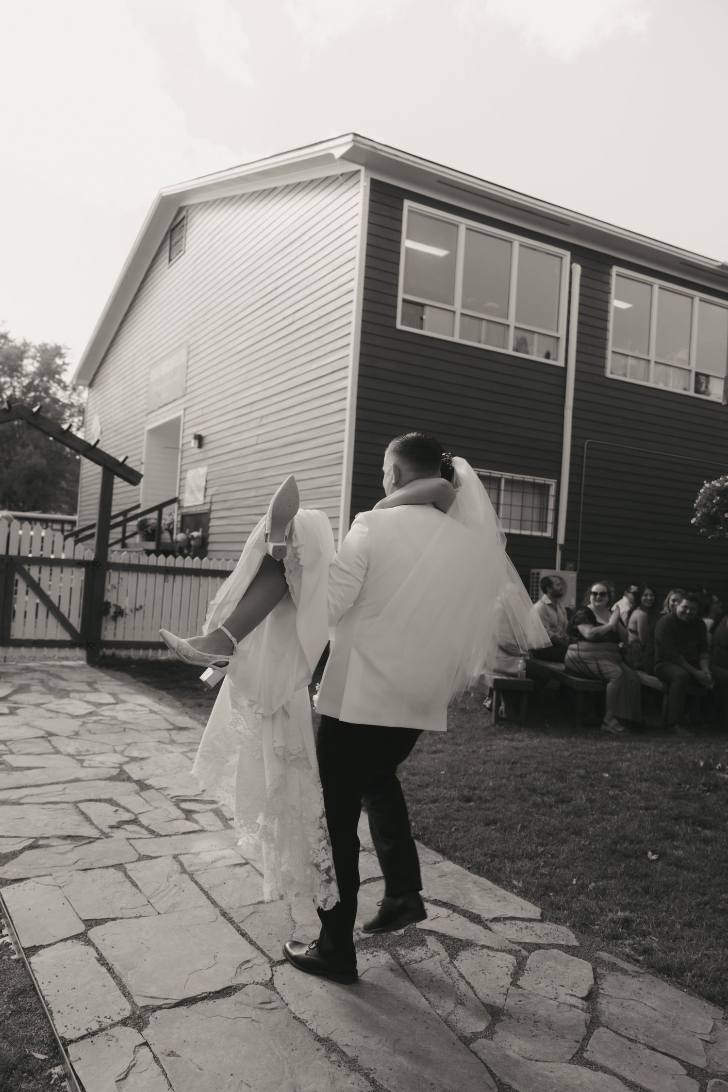 A series of black and white photos showing a couple walking along a stone pathway outside a house.