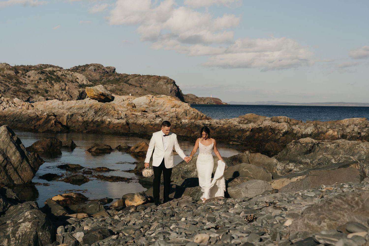 A scenic coastal landscape with rocky outcrops and ocean views along a rugged shoreline at sunset.