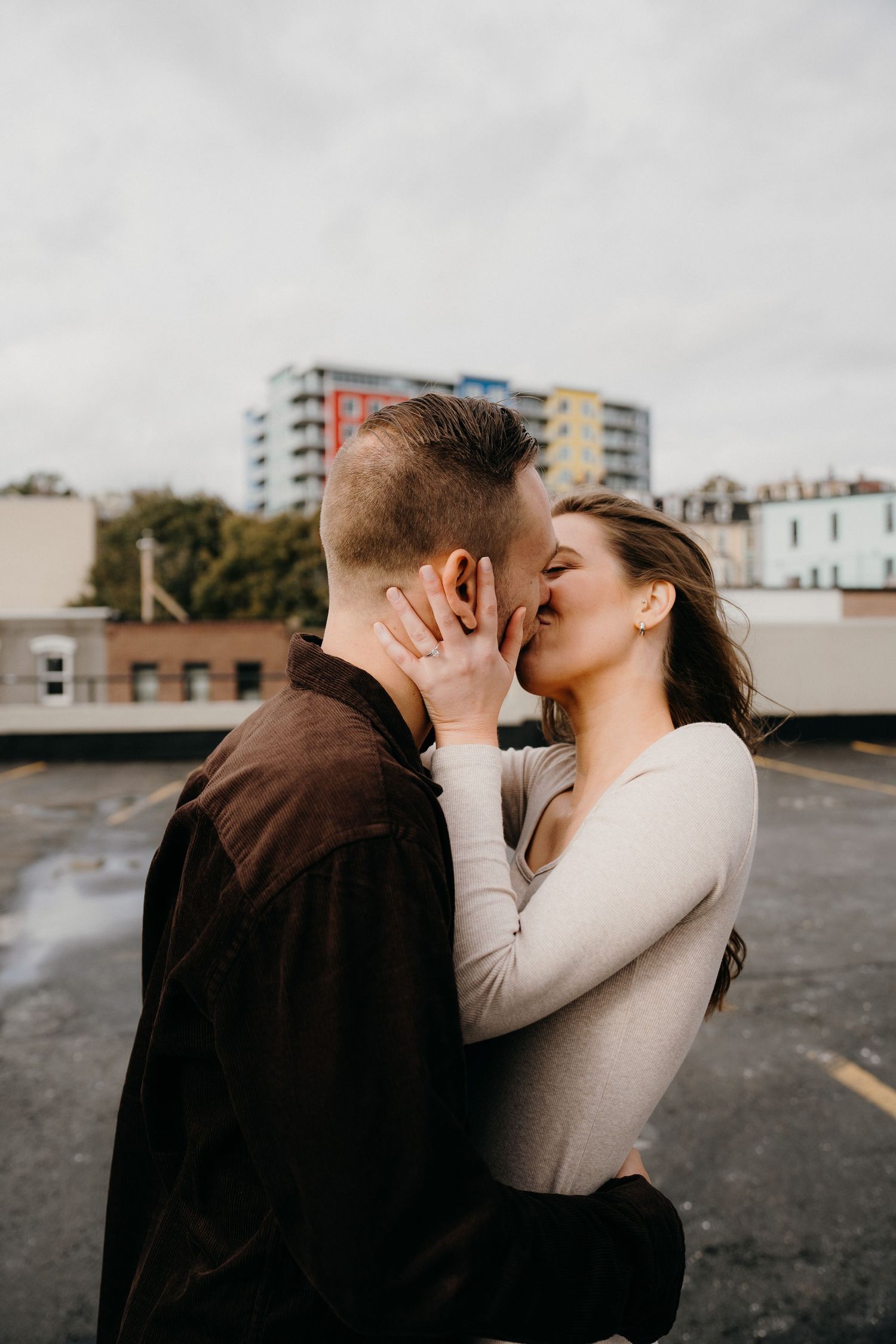 An intimate moment between a couple with urban architecture in the background.