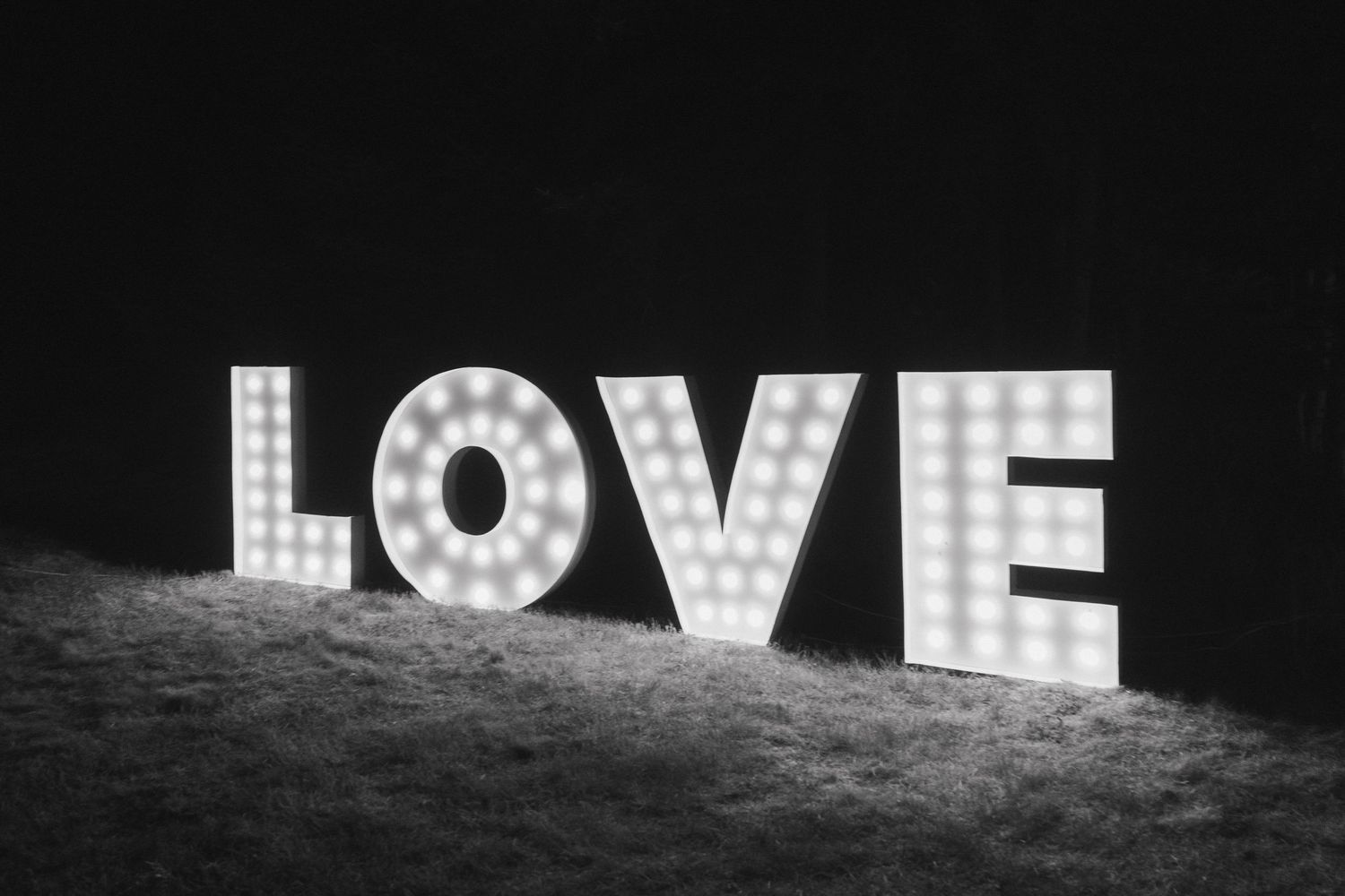 Illuminated marquee letters spelling LOVE glowing against a dark background.