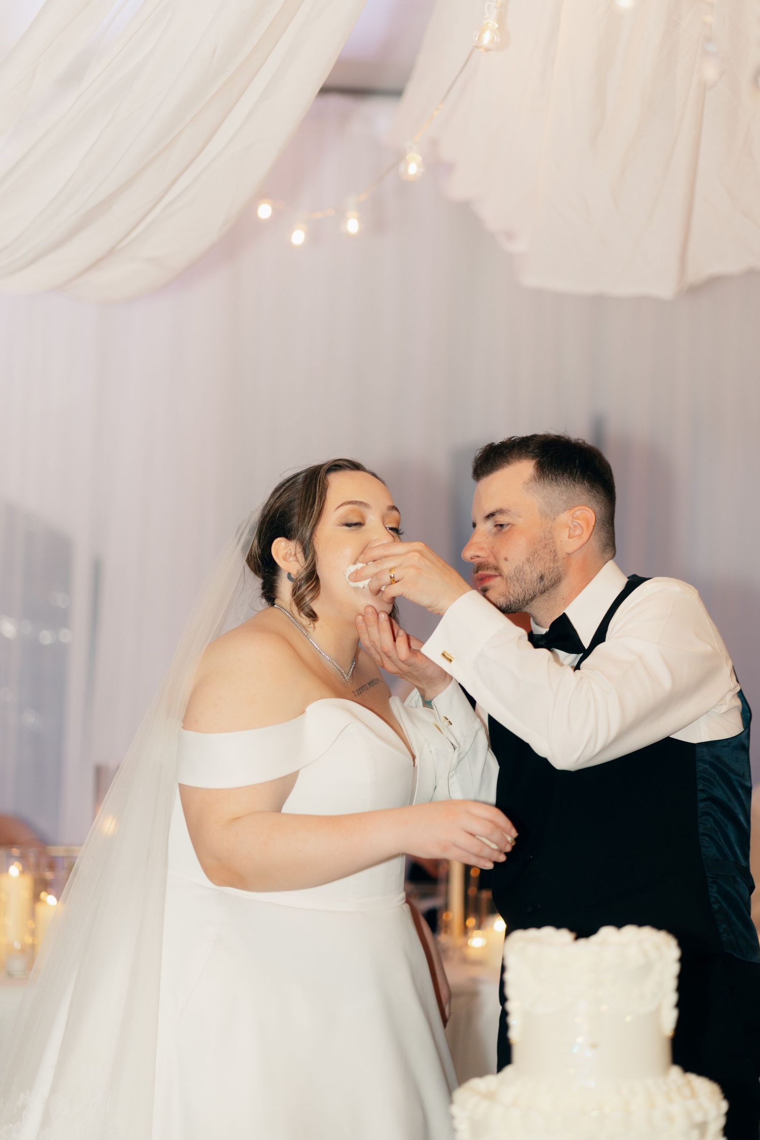 A couple feeds each other wedding cake in a traditional reception moment.