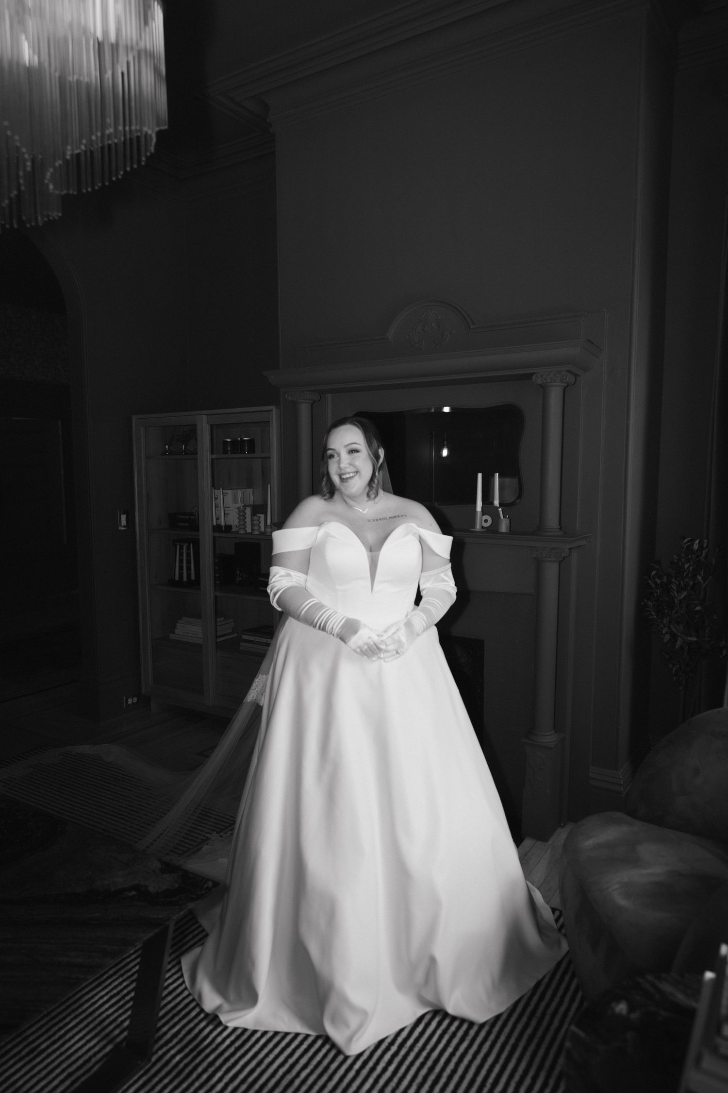 A dramatic black and white photograph of a wedding dress in an elegant interior setting.