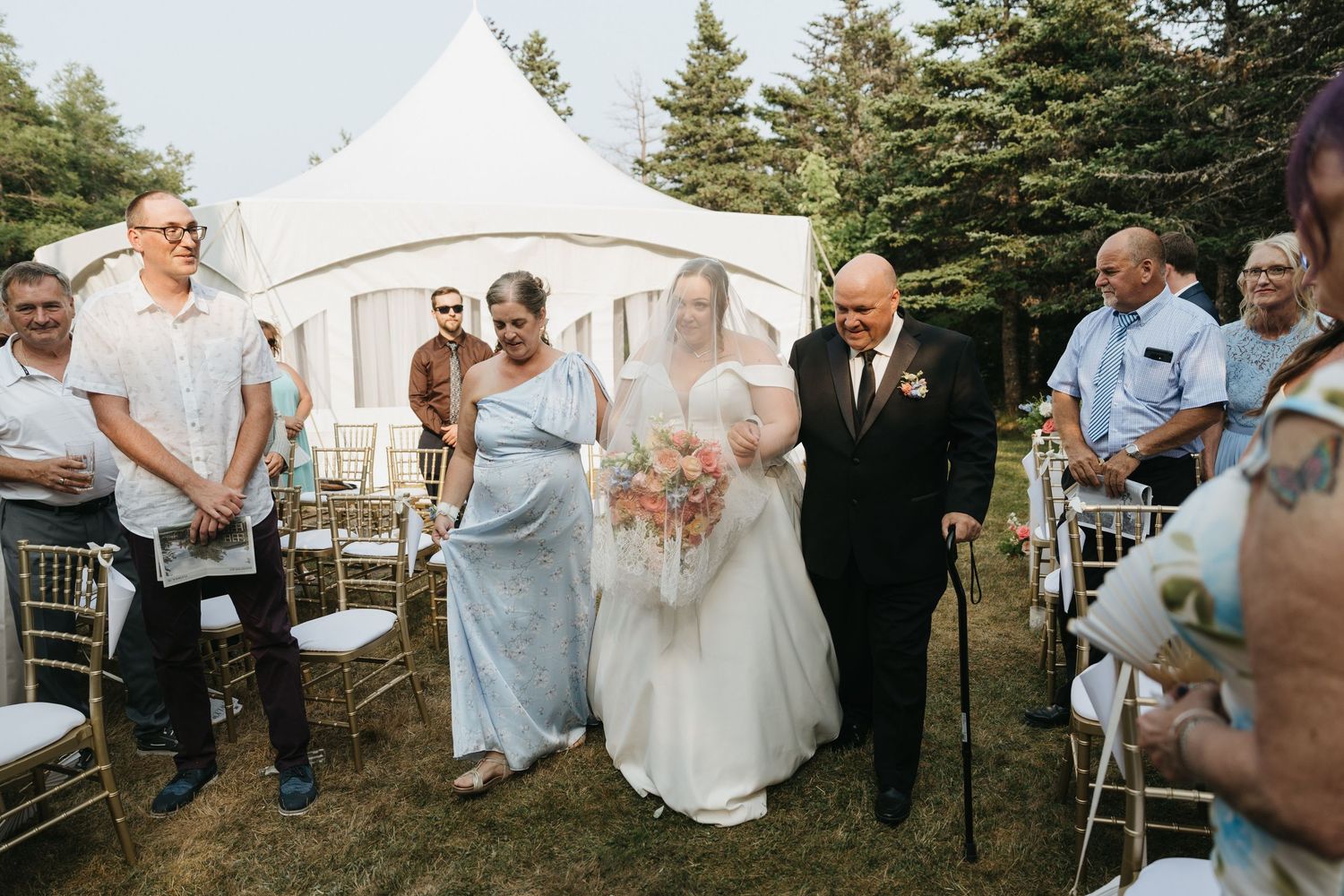 Casual outdoor wedding reception with guests mingling near white tents.