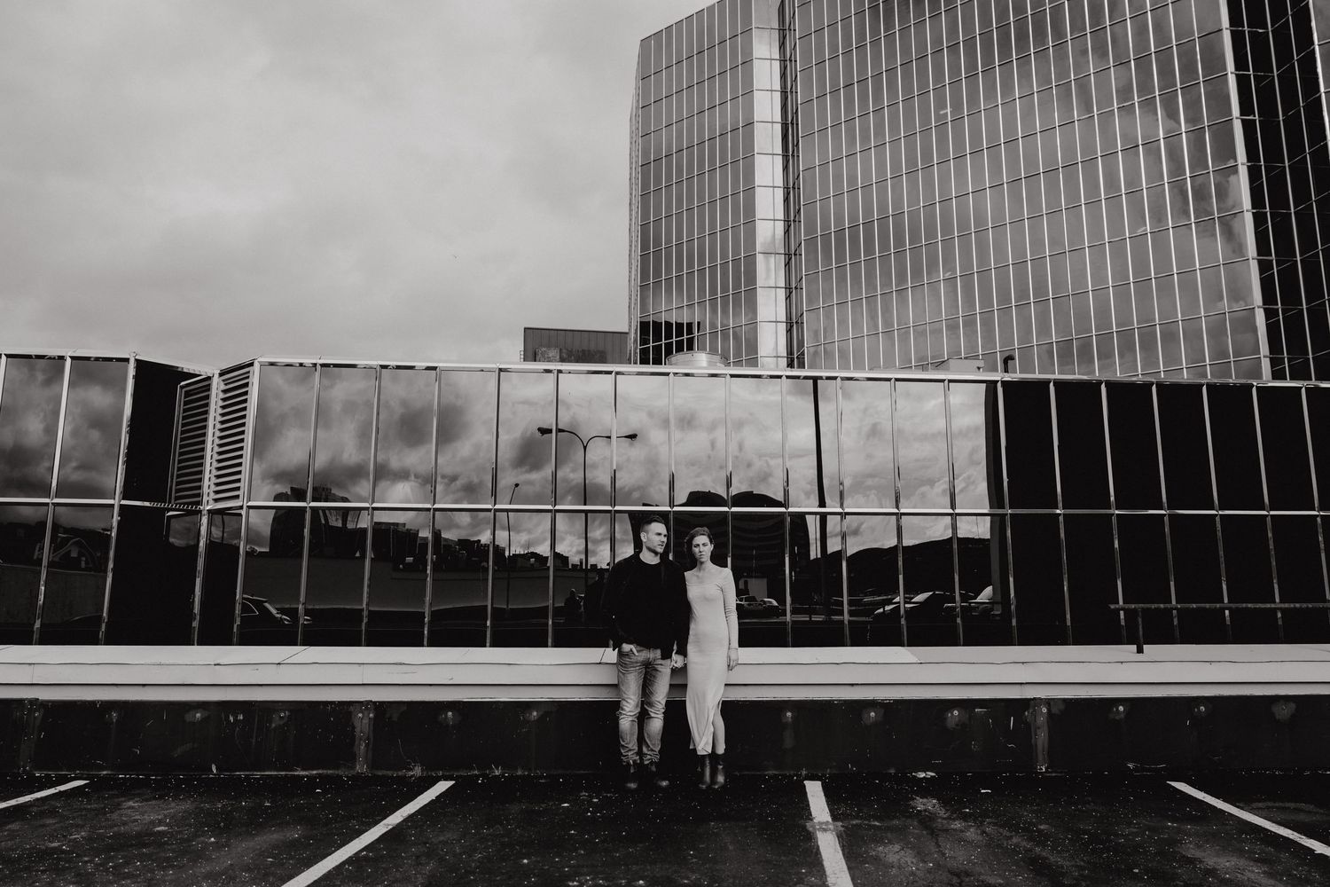Black and white panoramic view of modern glass office buildings against cloudy sky.
