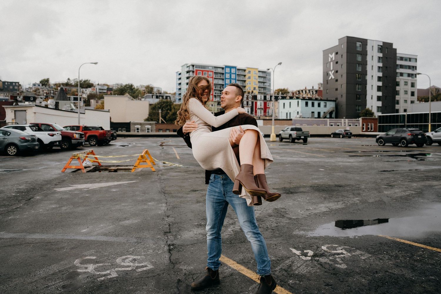 Dynamic dance lift photographed against modern city architecture and overcast sky.