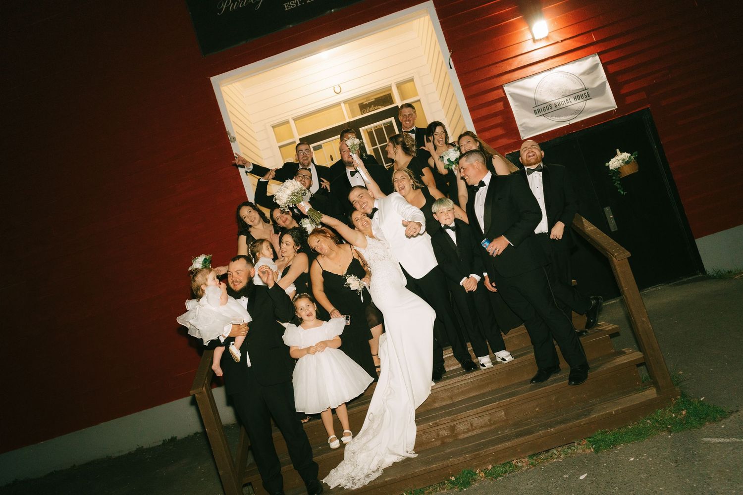 Guests dancing and celebrating at a dimly lit indoor wedding reception with red walls.