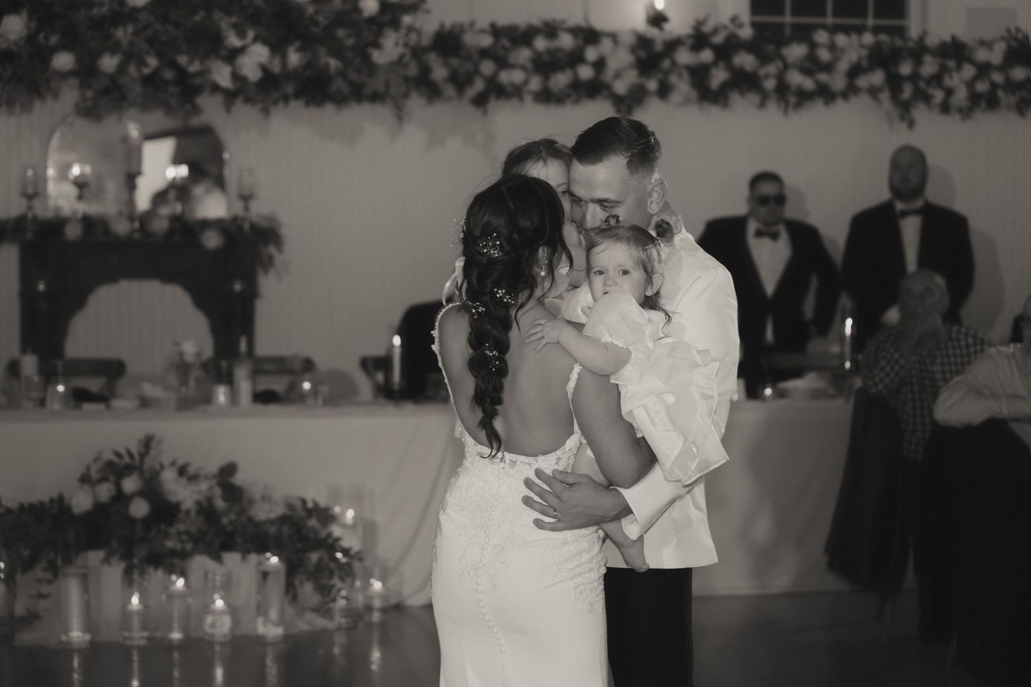 A couple shares their first dance at a wedding reception while guests watch from the surrounding tables.