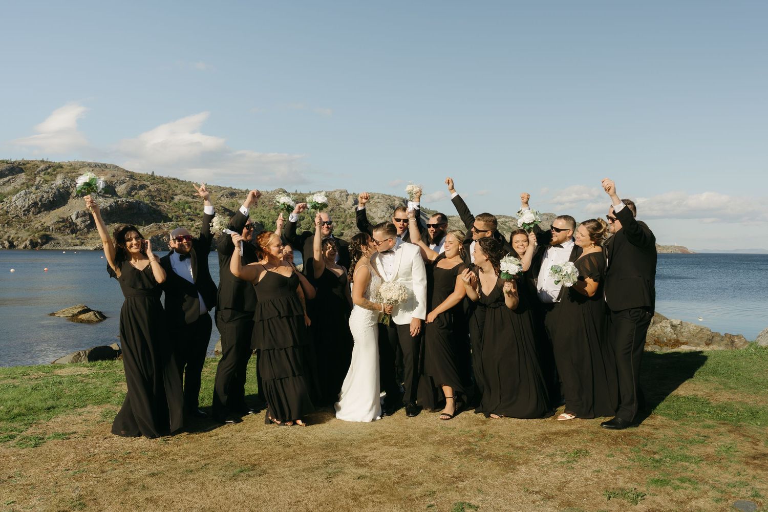 A sequence of wedding party group photos on a scenic coastal cliff with ocean views in the background.