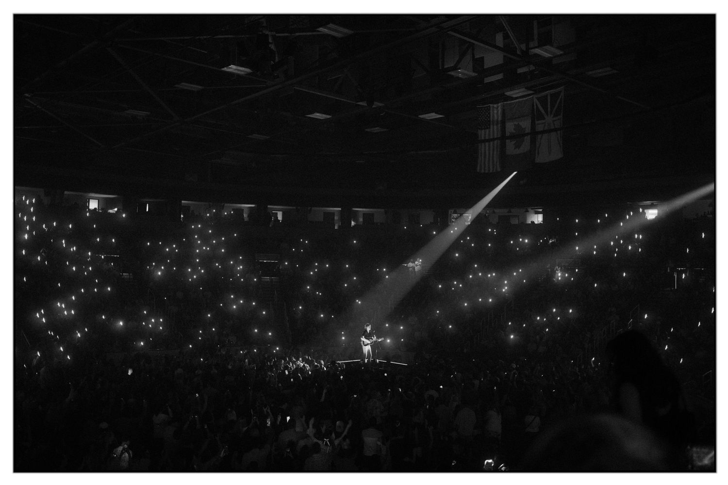 Aerial view of a large concert arena filled with glowing lights from thousands of attendees during a nighttime performance.