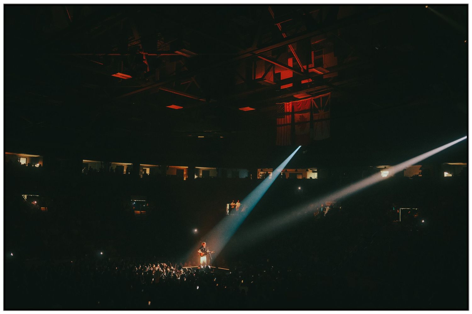 Concert stage illuminated with dramatic blue spotlights shining through atmospheric haze during a live performance.