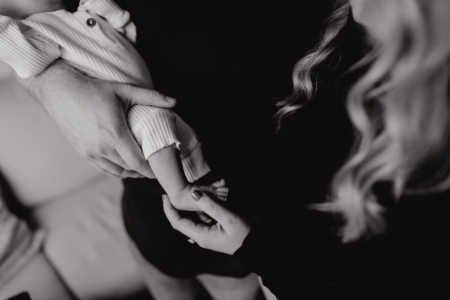 Artistic black and white capture of parents bonding with their newborn.