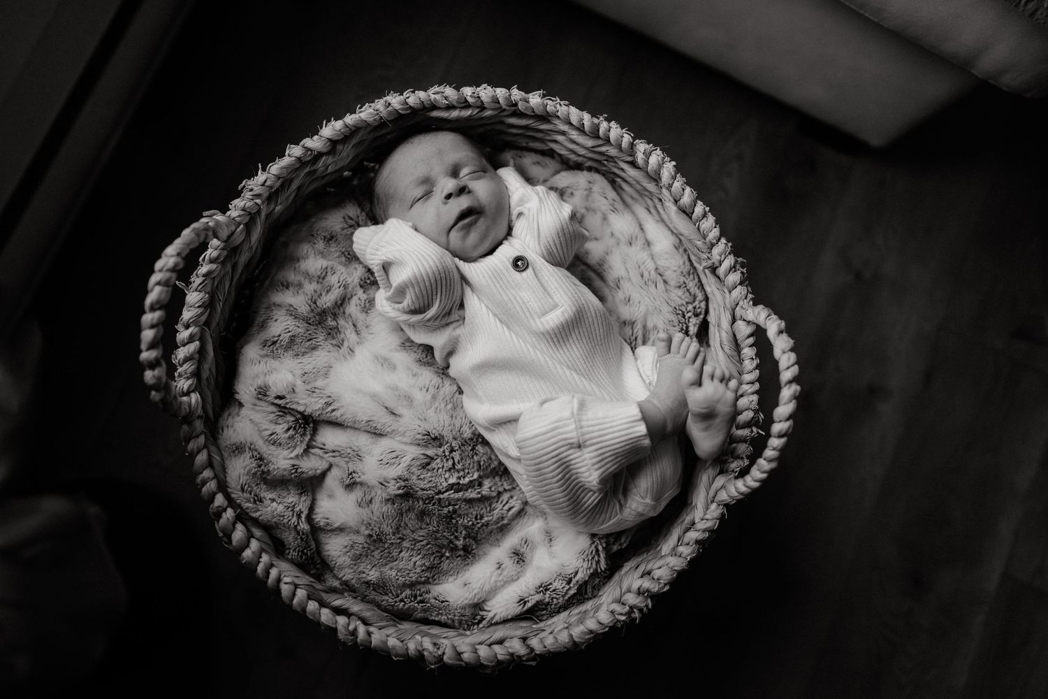 A tender moment captured in black and white of a sleeping infant in a basket.