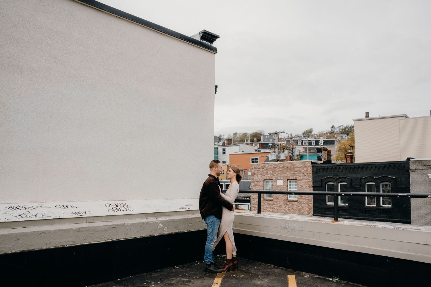 Empty rooftop space with white walls and urban buildings visible in the distance.
