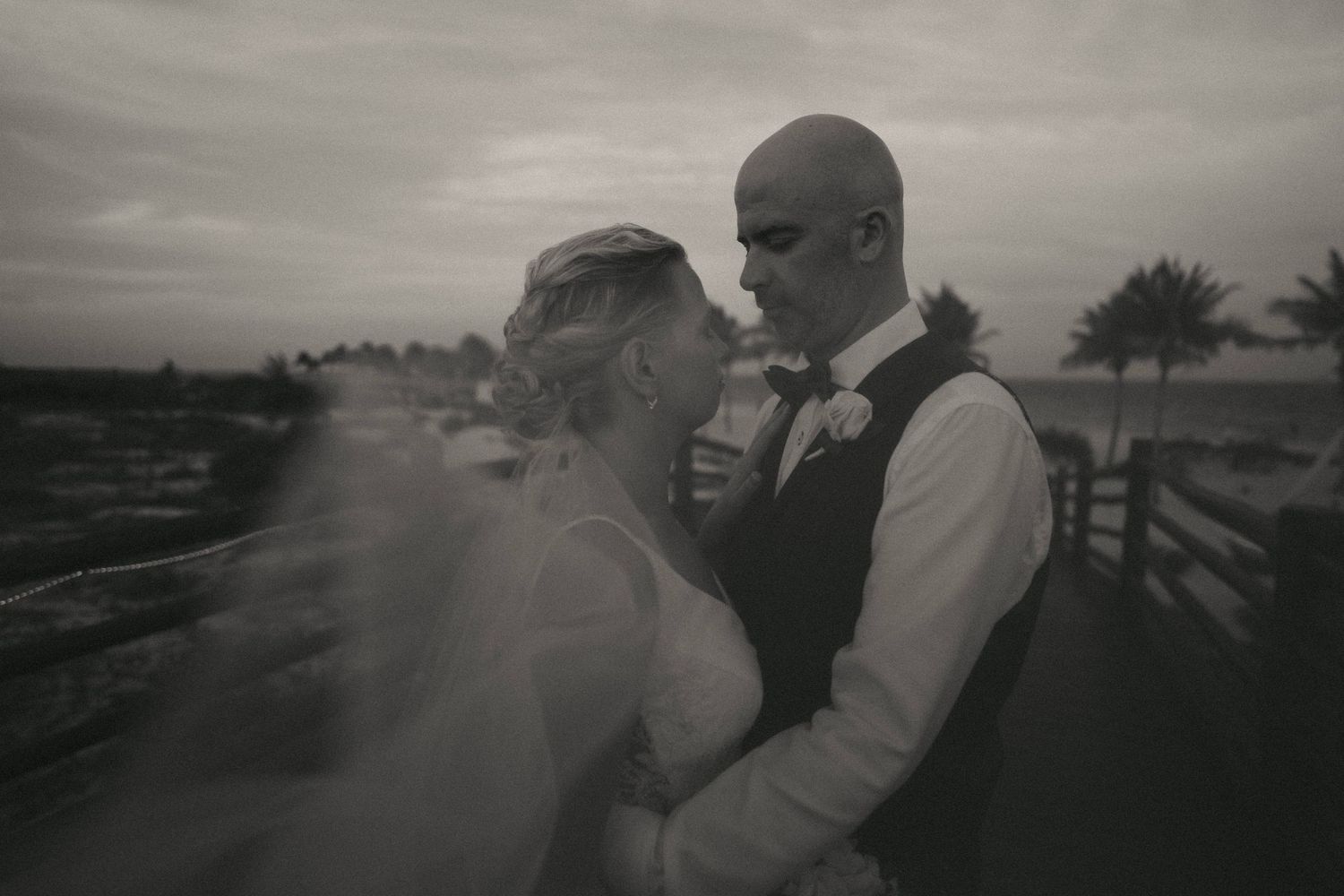 Black and white wedding portraits captured on a scenic beachfront boardwalk.
