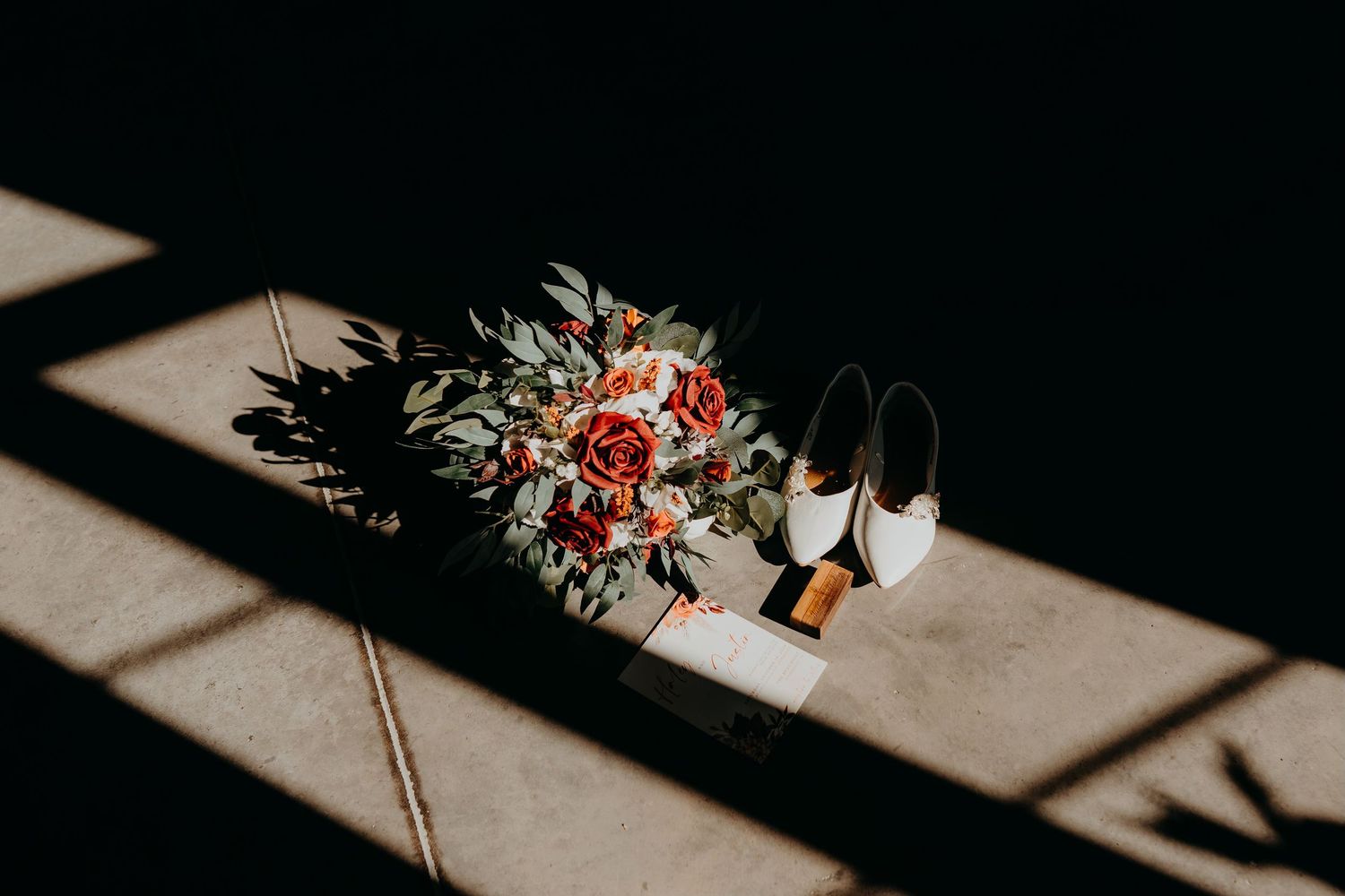 Wedding flowers and decor casting dramatic shadows on a light surface in artistic composition.