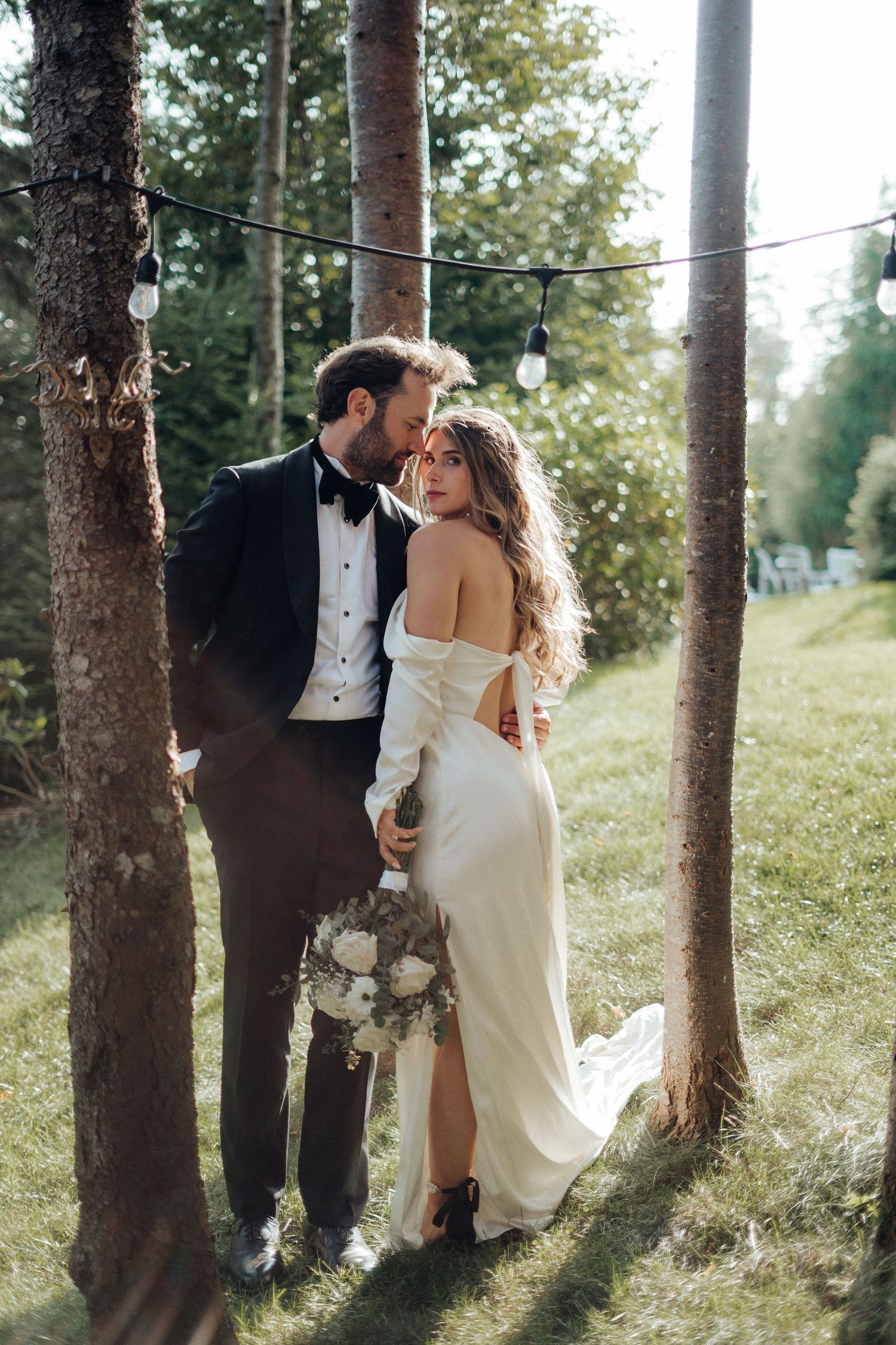 Romantic forest wedding portraits with sunlight streaming through pine trees.
