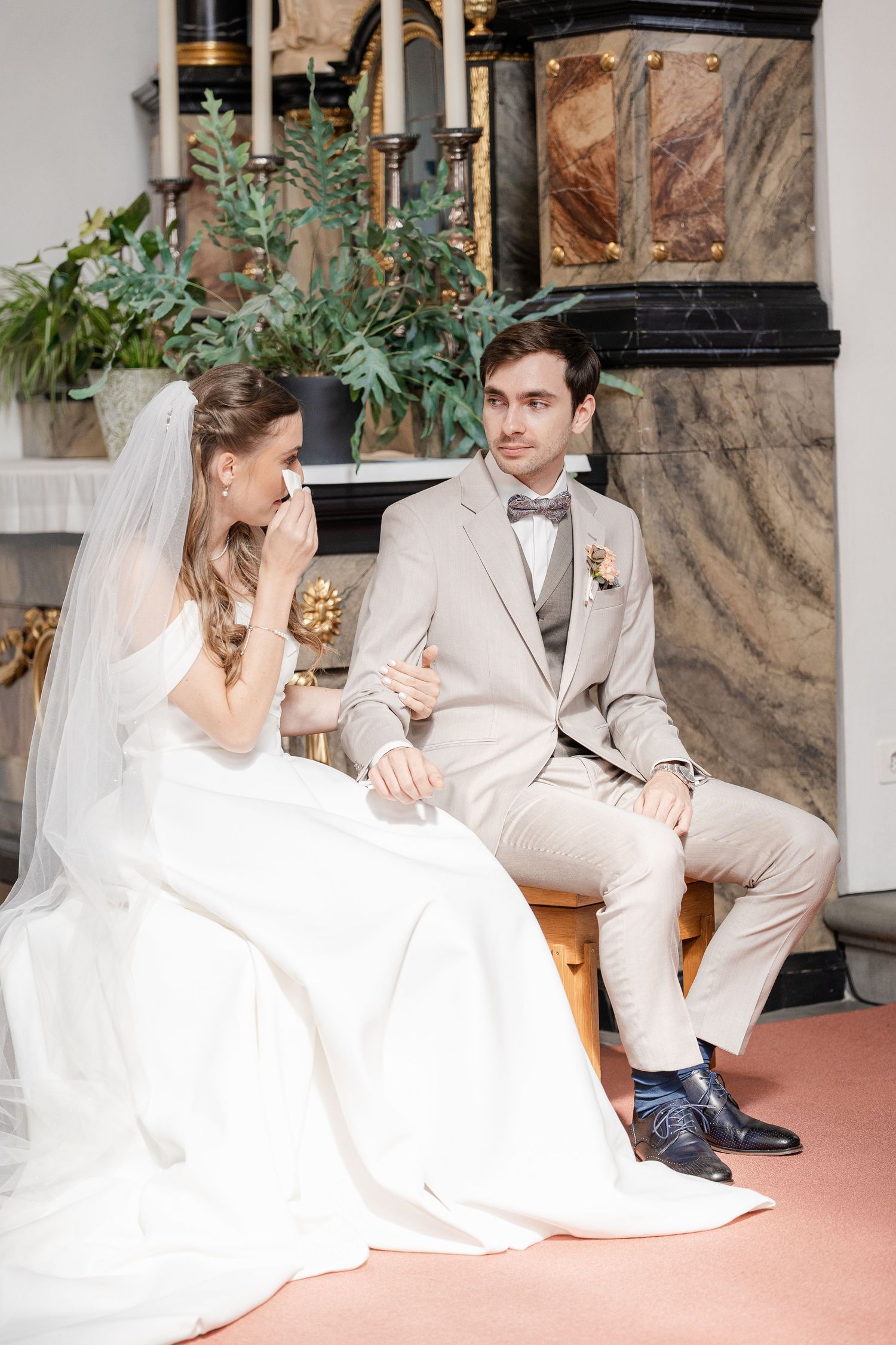 A bride and groom share intimate moments while sitting together during their wedding celebration.