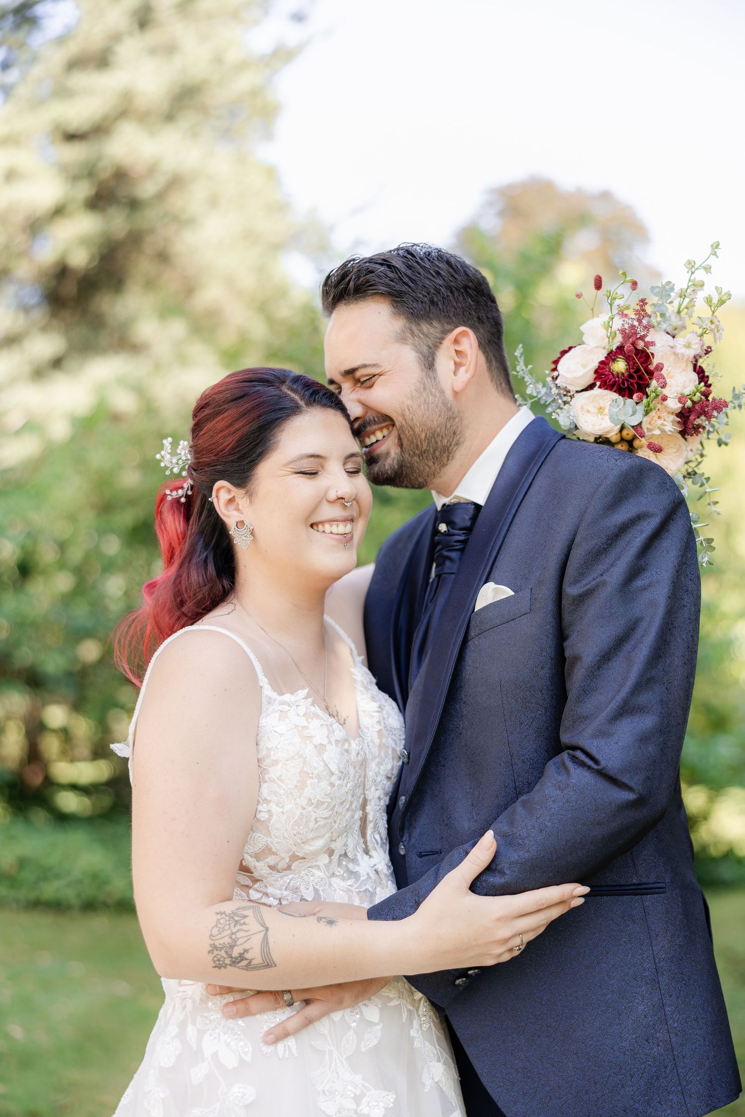A romantic wedding couple shares intimate moments in a garden setting while wearing navy and white attire.