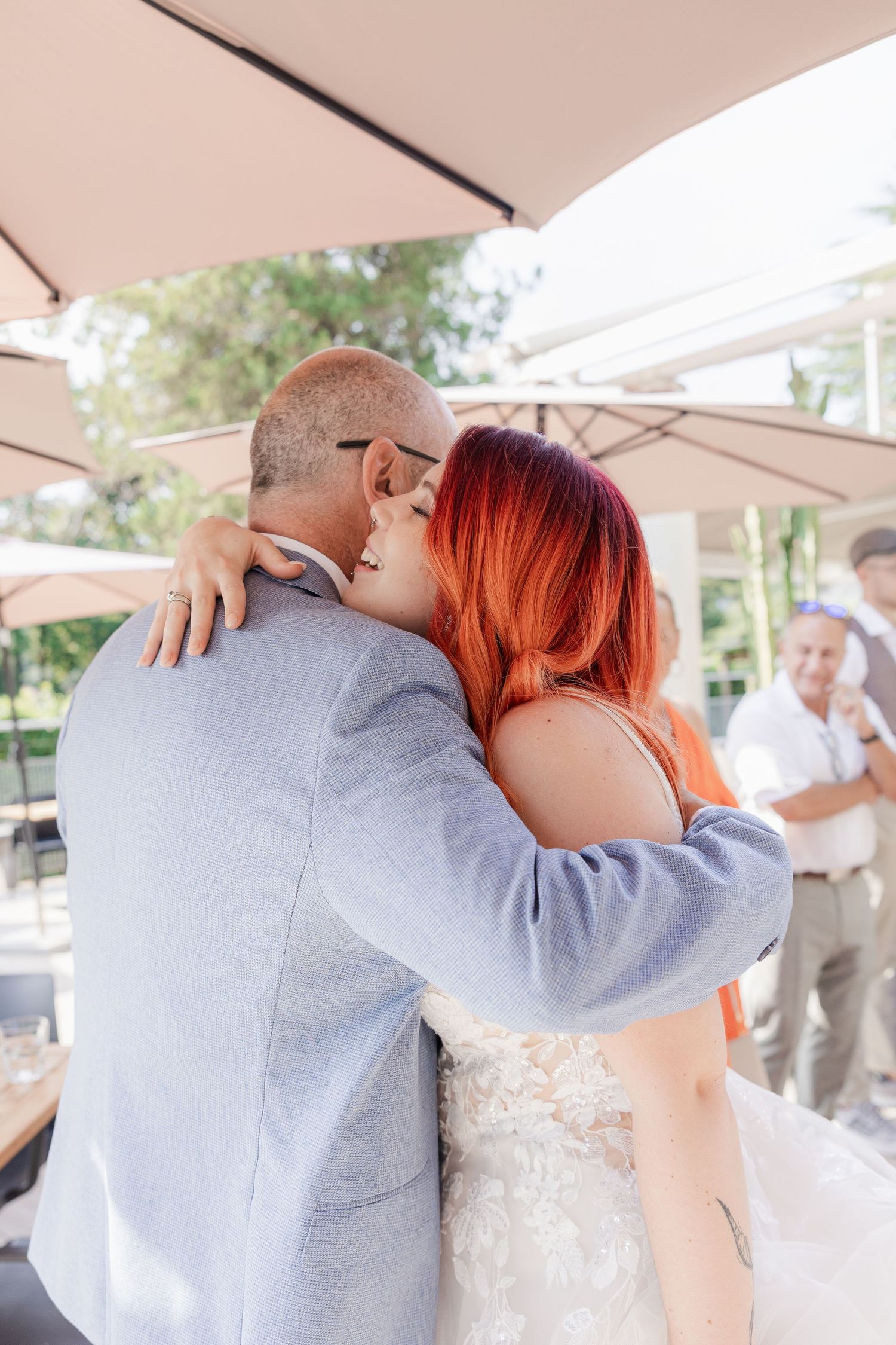 A couple embraces during their wedding ceremony under a white canopy at an outdoor venue.