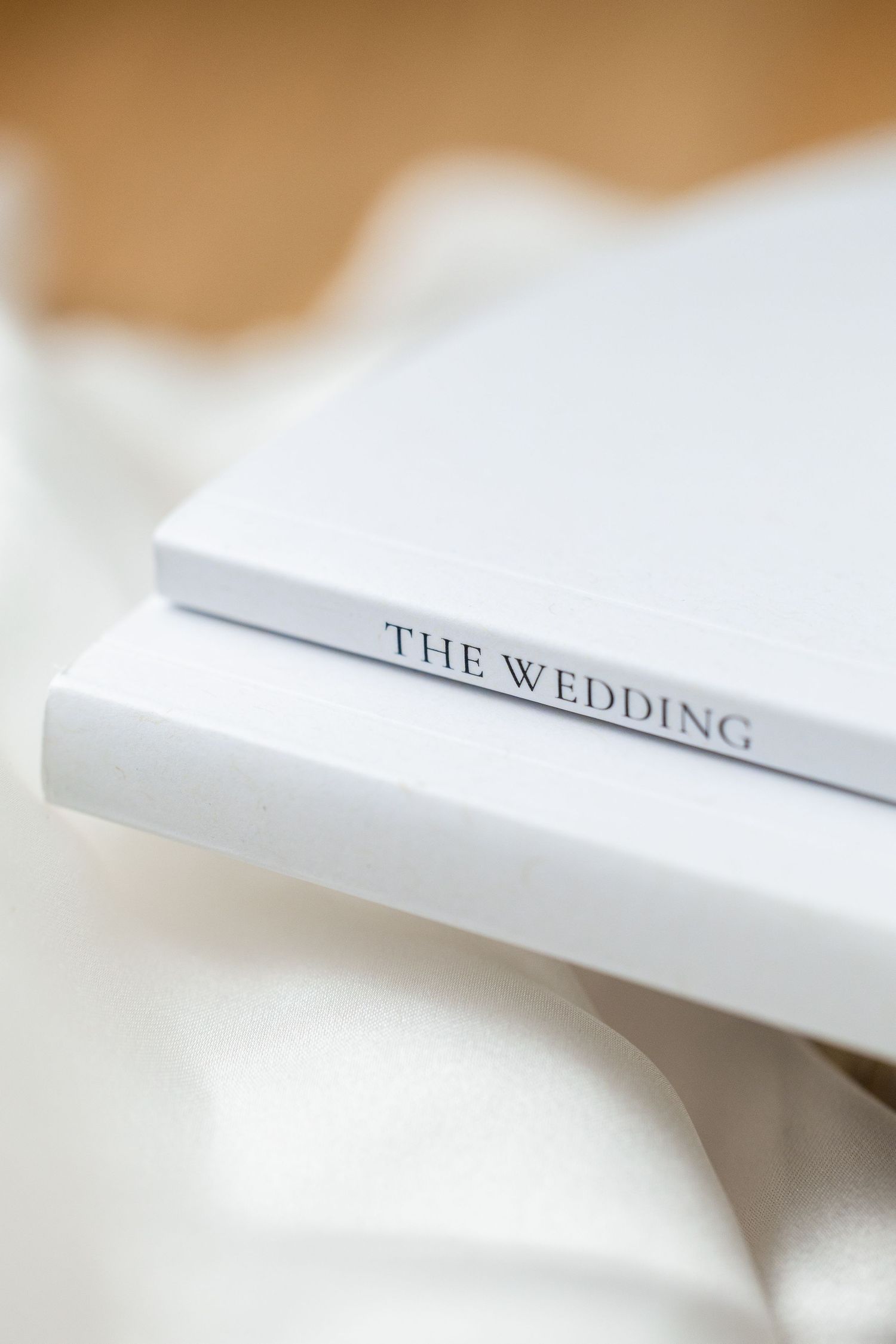 Close-up view of white book pages with the word 'WEDDING' visible on the spine against a light beige background.