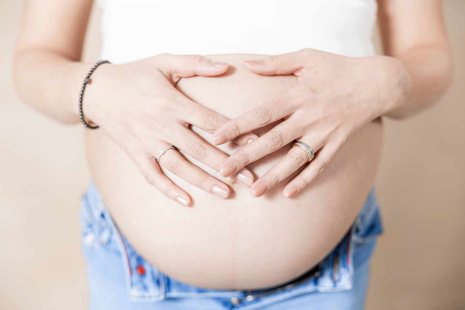 Pregnant woman's growing belly shown in series of progressive photos wearing blue shorts and white top.