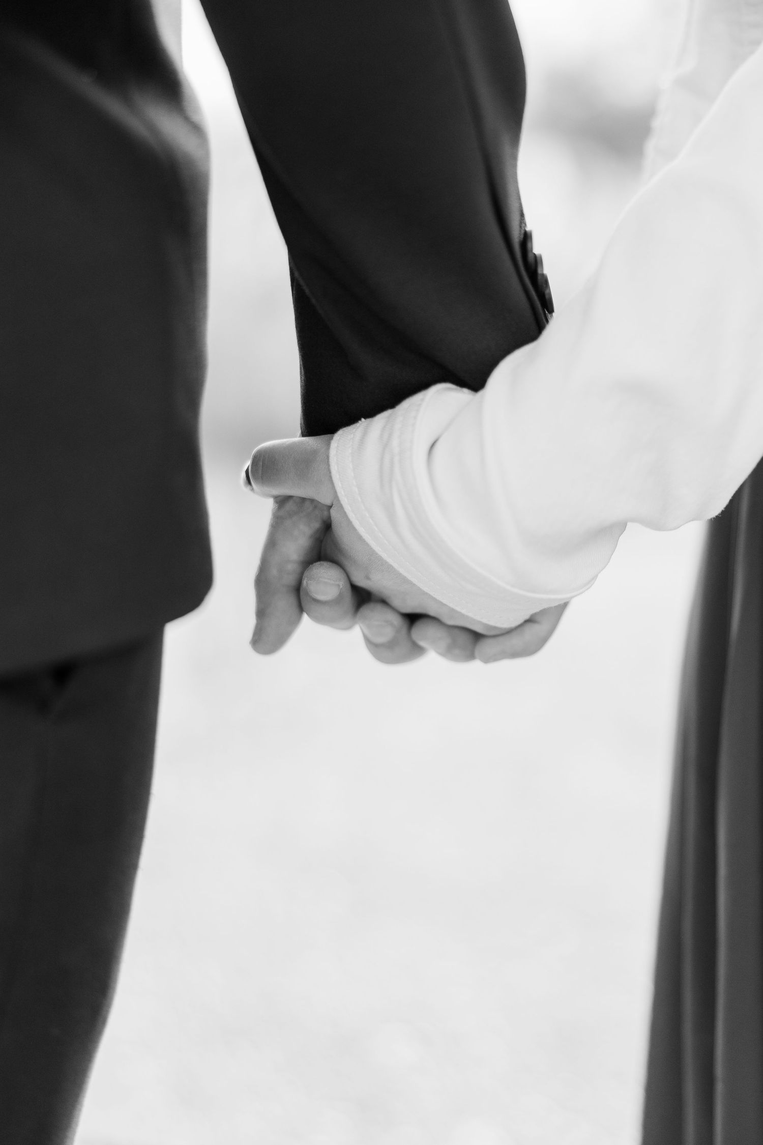 Black and white photo of a bride and groom holding hands at their wedding ceremony.