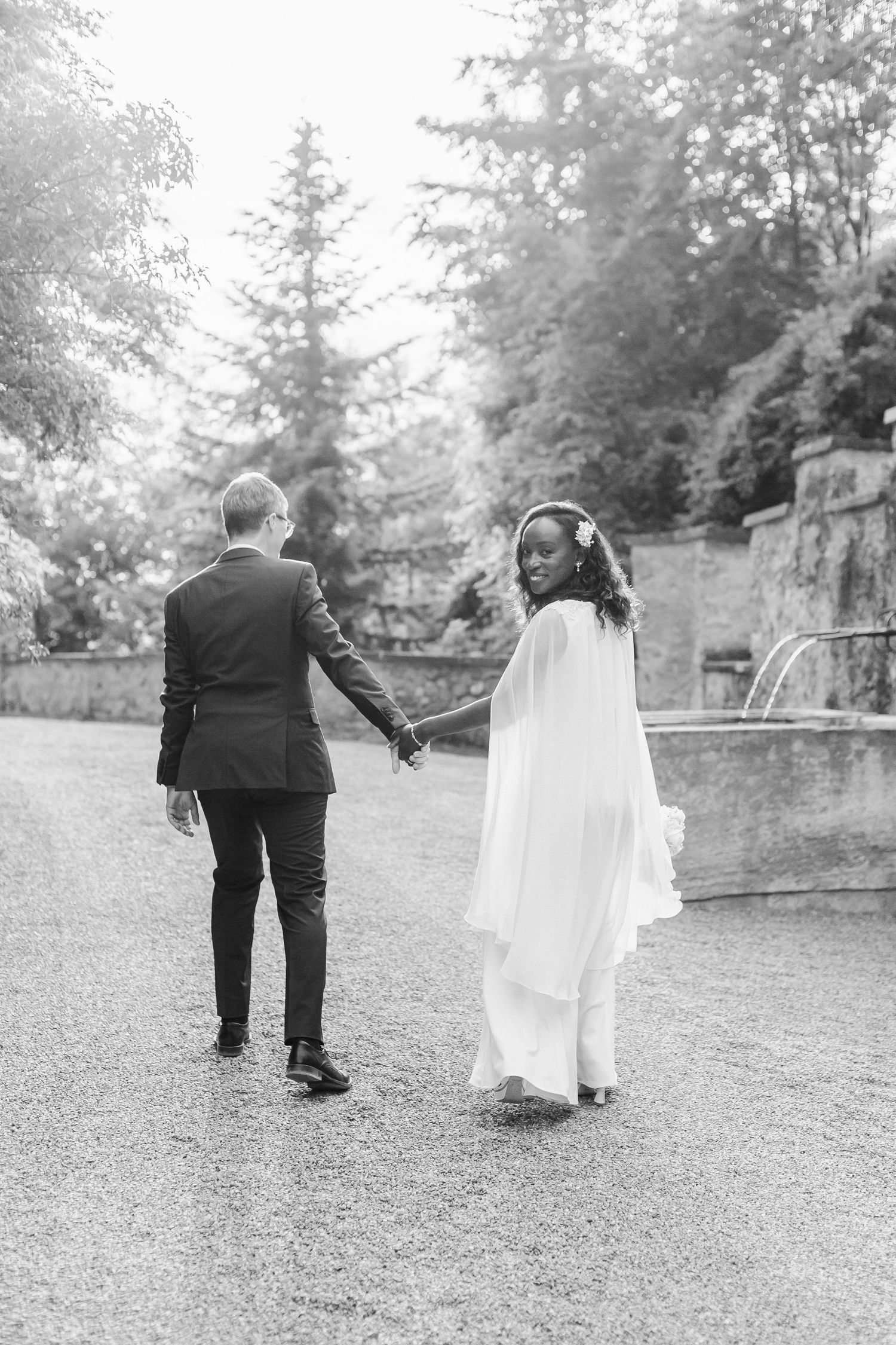 Black and white wedding photo sequence showing couple walking away together on a gravel path surrounded by evergreen trees.