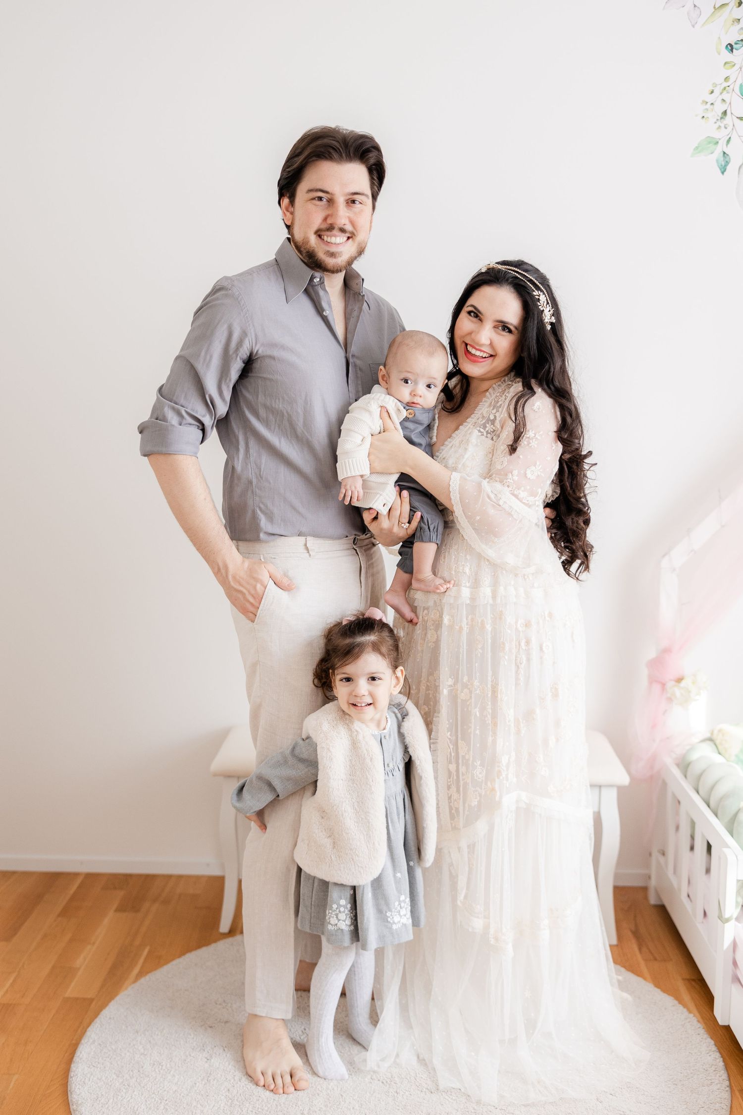 Modern family portrait in soft neutral colors against a white wall backdrop with pastel decor.