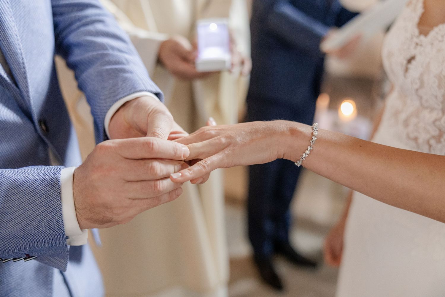 Close-up sequence of hands exchanging wedding rings during a marriage ceremony.