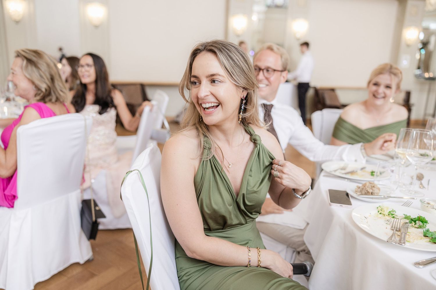 Guests seated at elegant white-clothed dining tables during a celebration event.