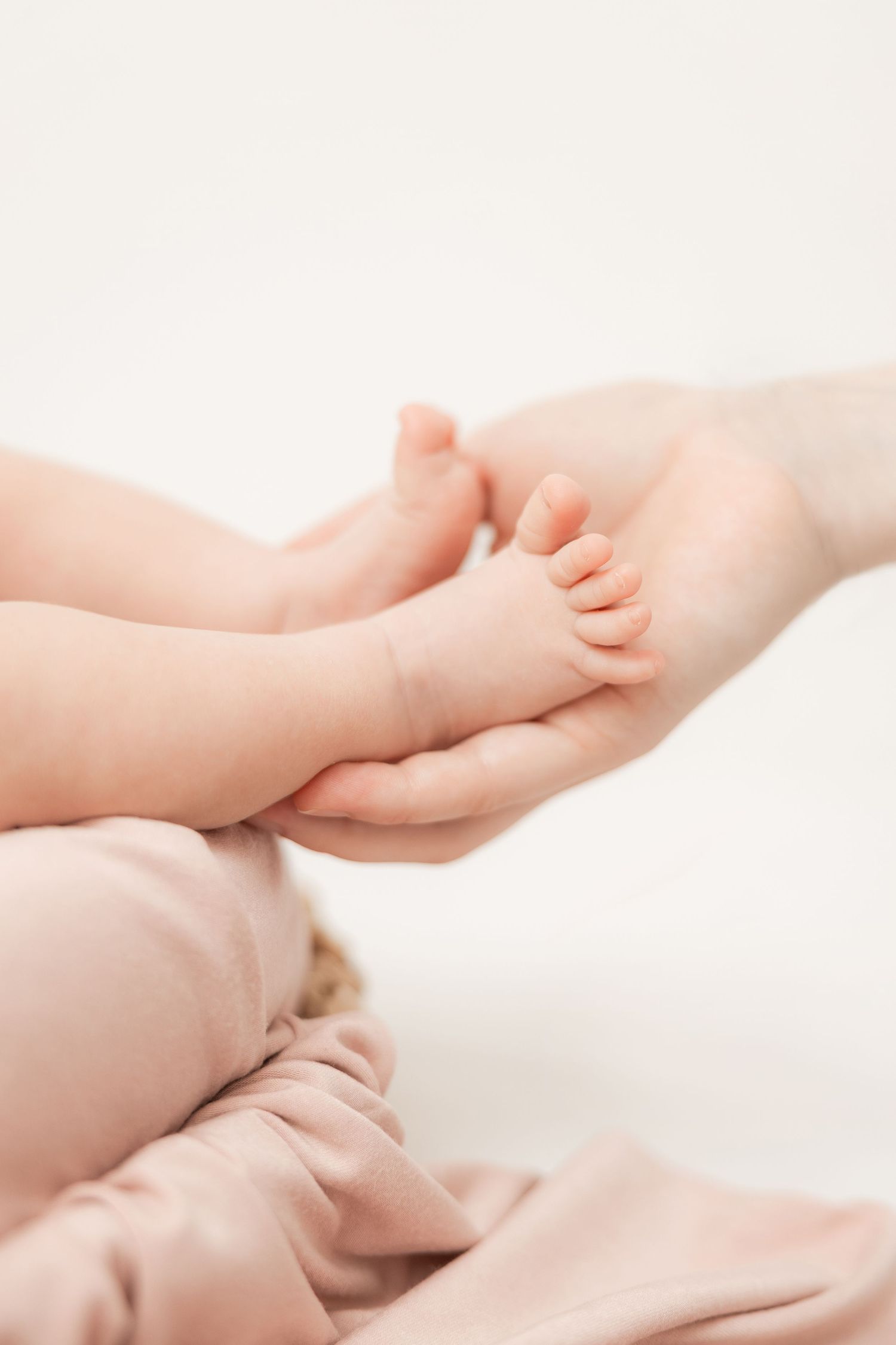 Close-up of gentle baby feet being softly touched and massaged on white background.