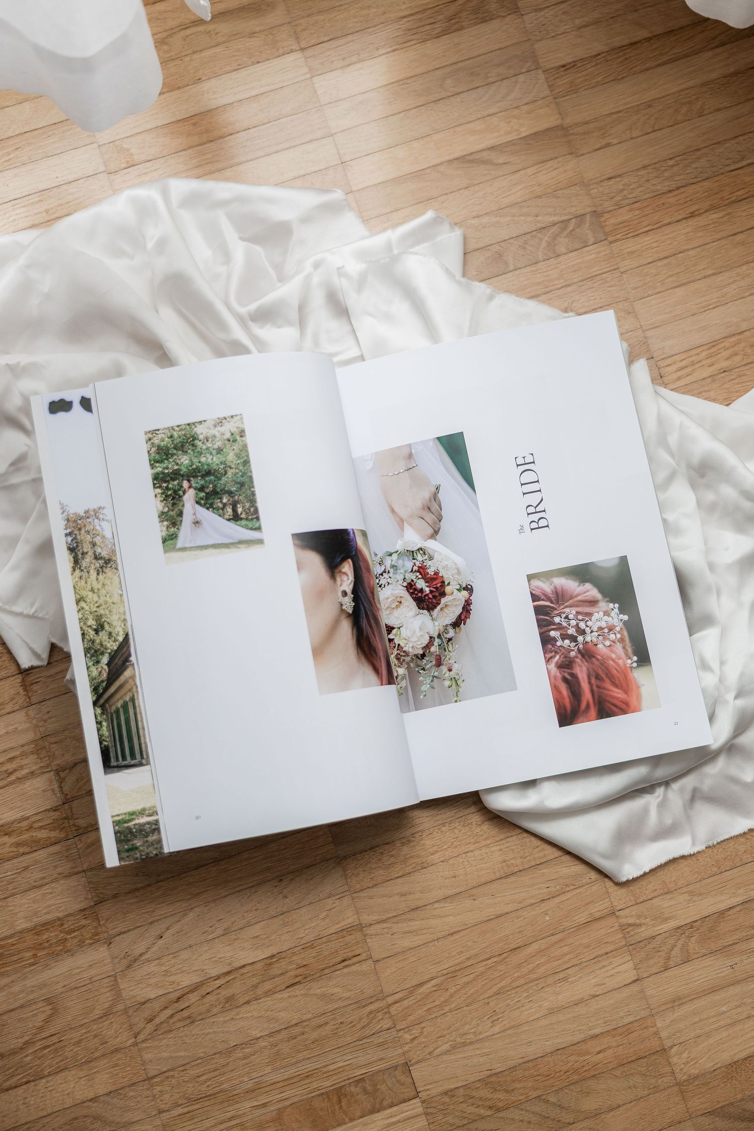 White wedding photo albums with professional photographs displayed on hardwood flooring.
