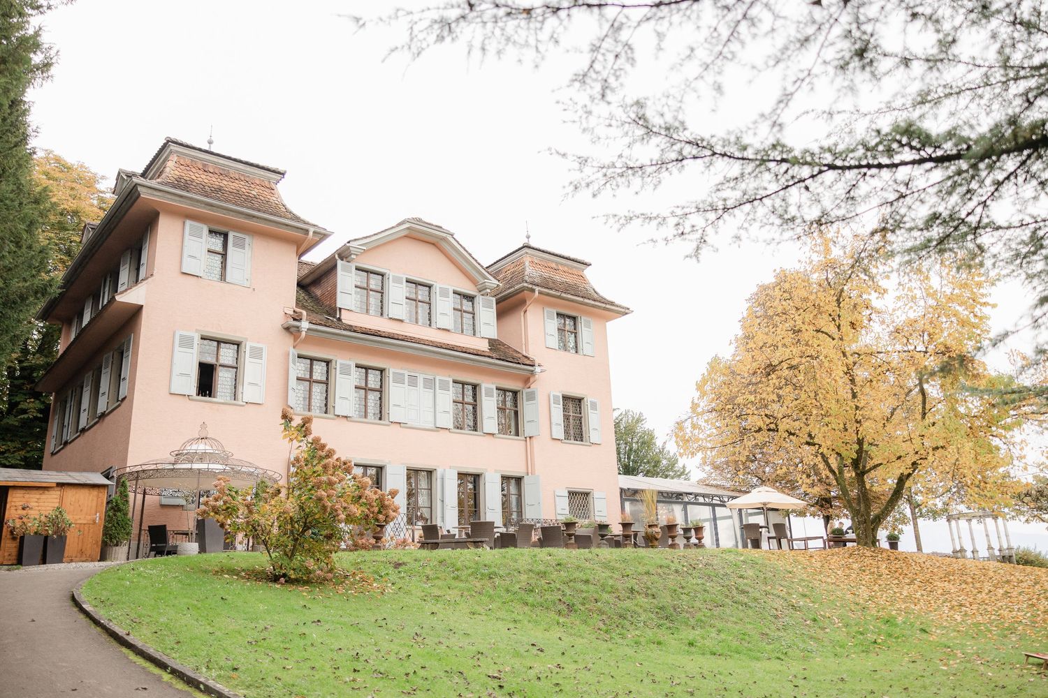 Panoramic exterior view of modern beige residential homes nestled among autumn trees on a hillside property.