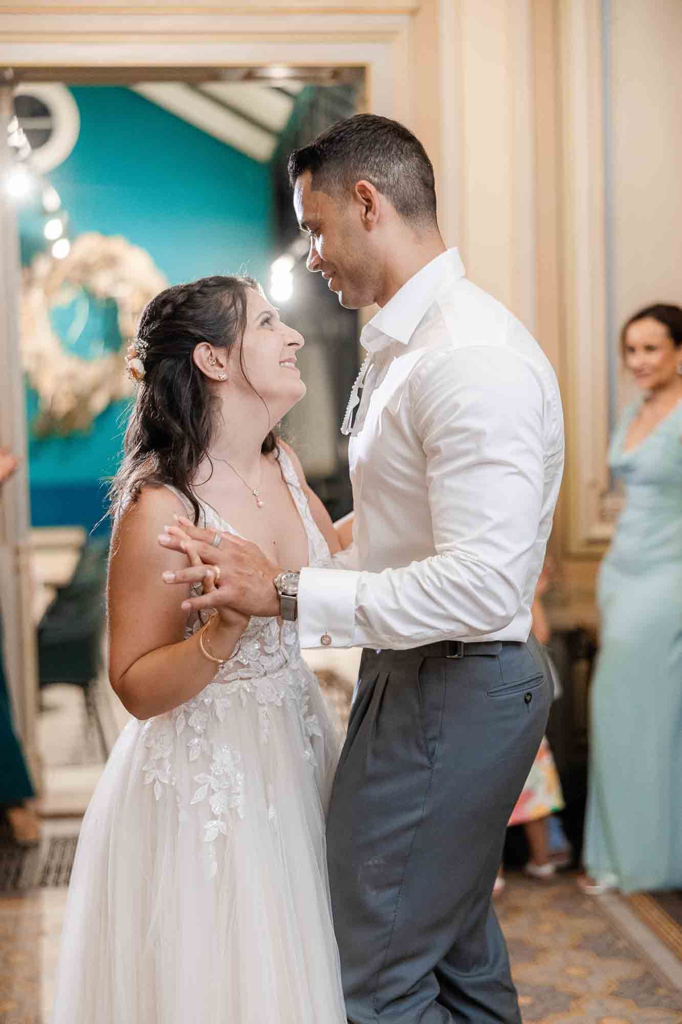 A bride and groom share their first dance, gazing lovingly at each other during their wedding reception.