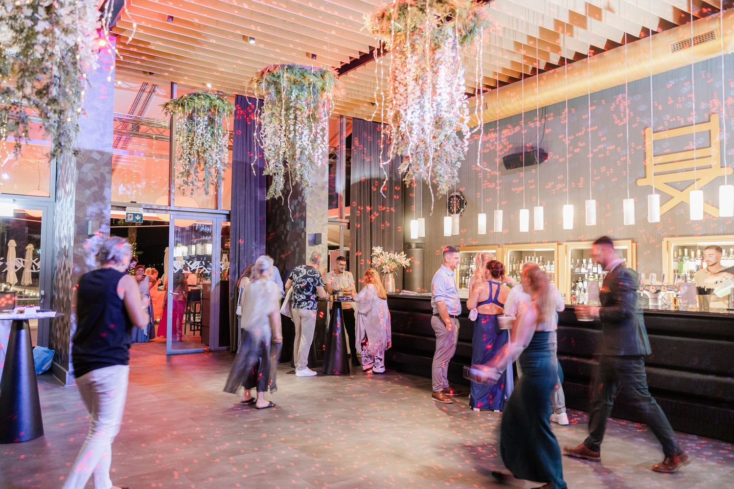 Panoramic view of an elegant ballroom with crystal chandeliers and guests mingling during an evening event.