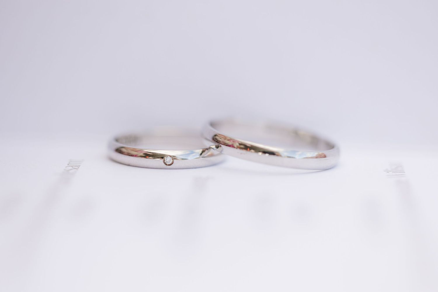White and silver wedding bands with diamonds displayed in different angles against a light background.