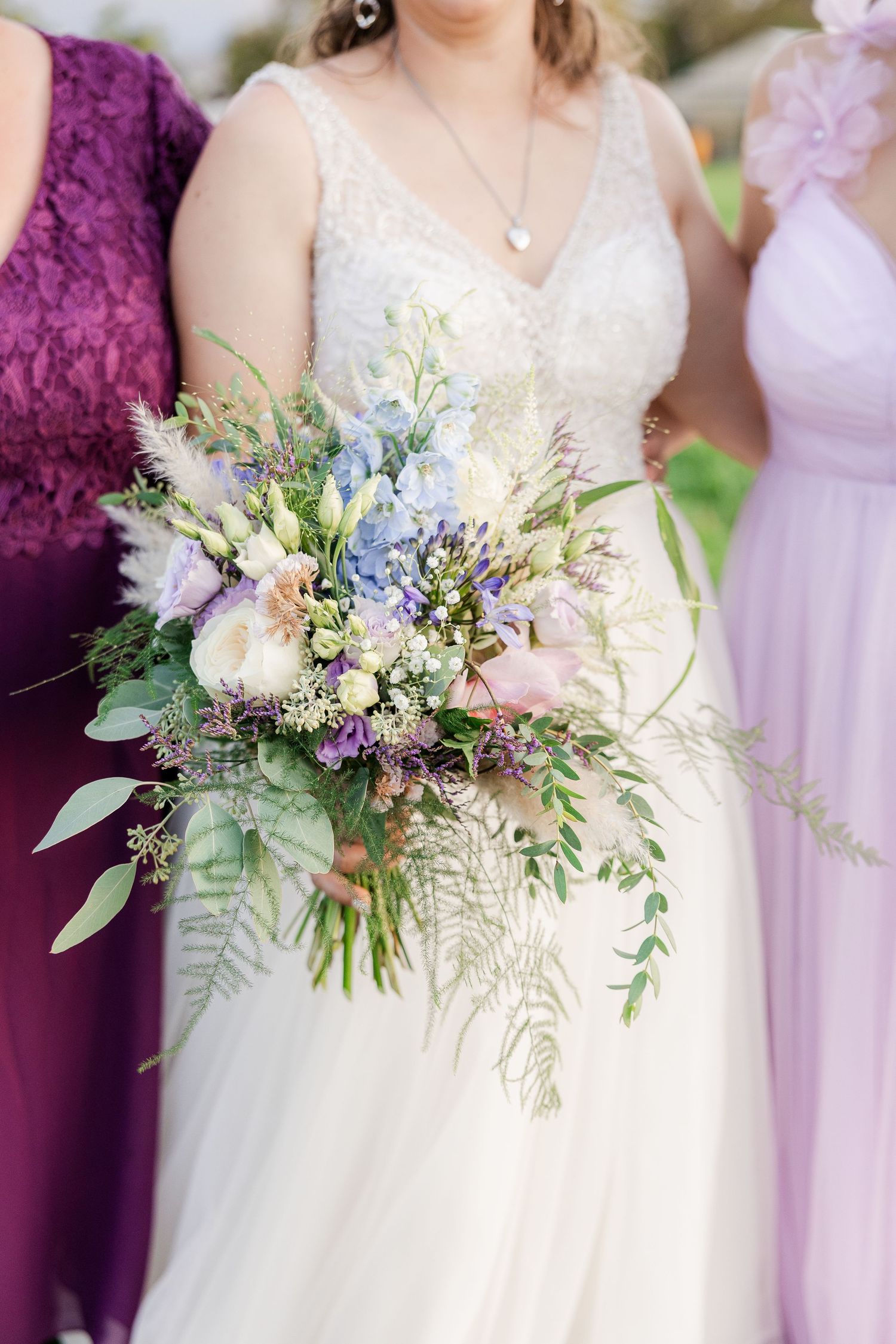 Close-up shot of an elegant bridal bouquet with delicate white and purple flowers against a soft purple backdrop.